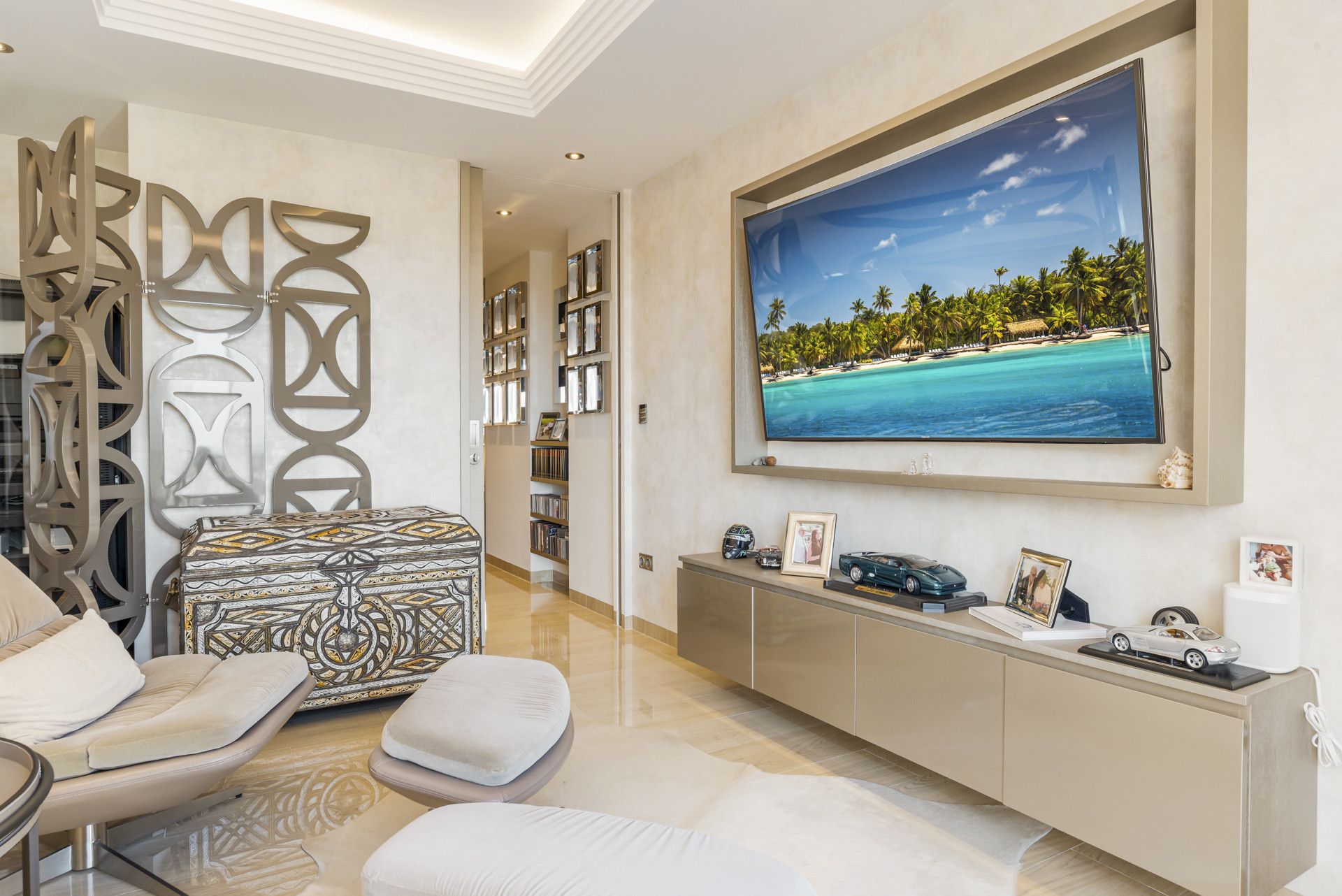 Living room with large wall-mounted TV, ornate screen, and plush seating.