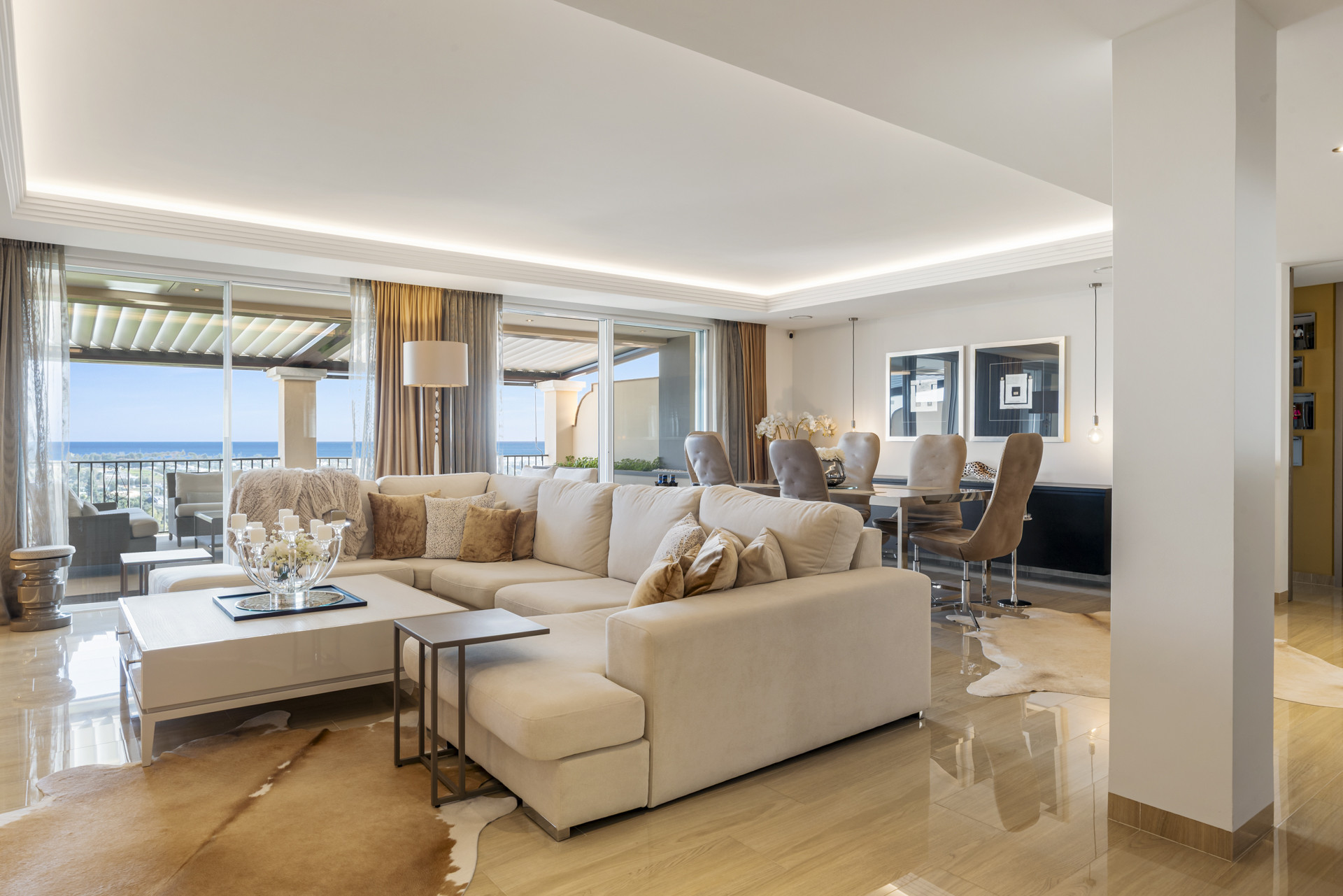 Spacious living room and dining area with a large sectional sofa, white coffee table, and ocean view terrace.