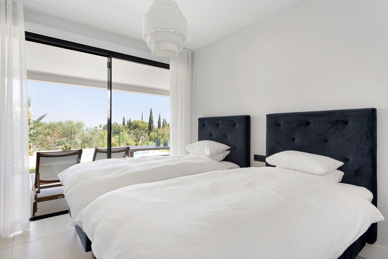 Bedroom with two single beds, white bedding, and a large sliding glass door opening to a patio.