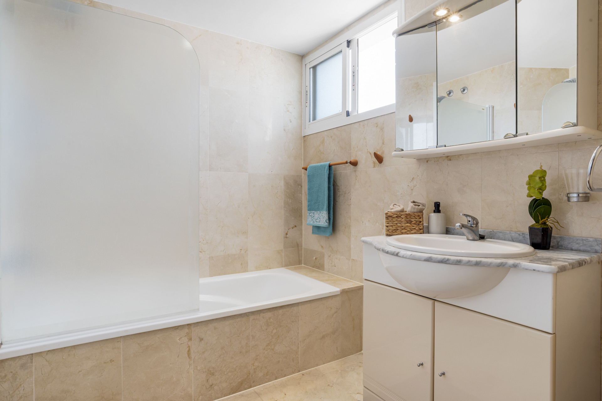 Bathroom featuring a tub, sink with mirror, and natural light from the window.