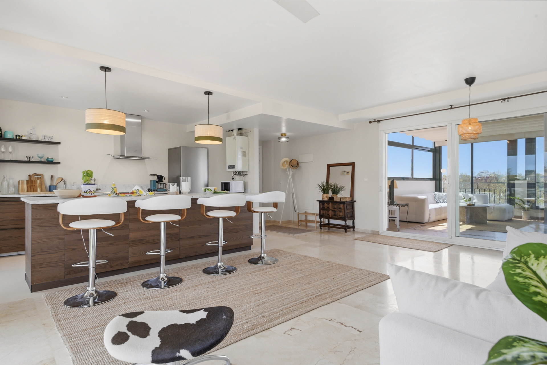 Open kitchen with a bar, modern appliances, and sliding glass doors to a balcony
