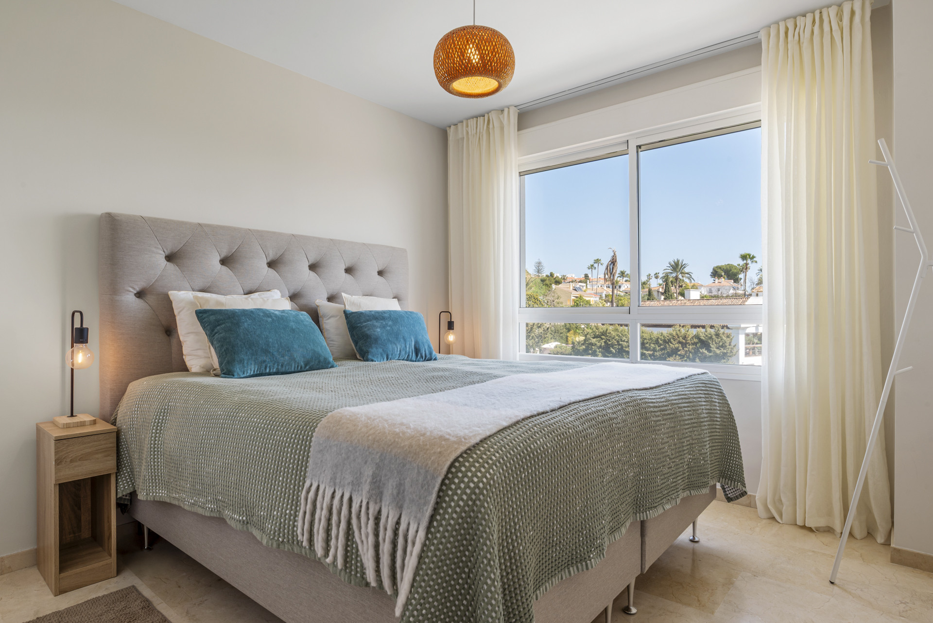 Bedroom featuring a tufted headboard, decorative pillows, and light fixtures