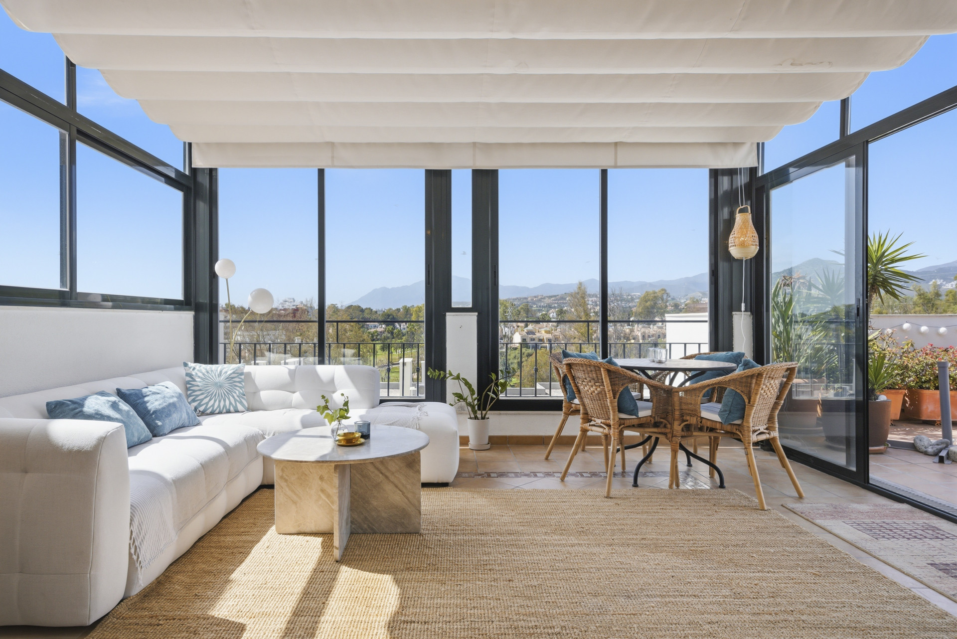 Spacious sunlit terrace with seating and mountain views.