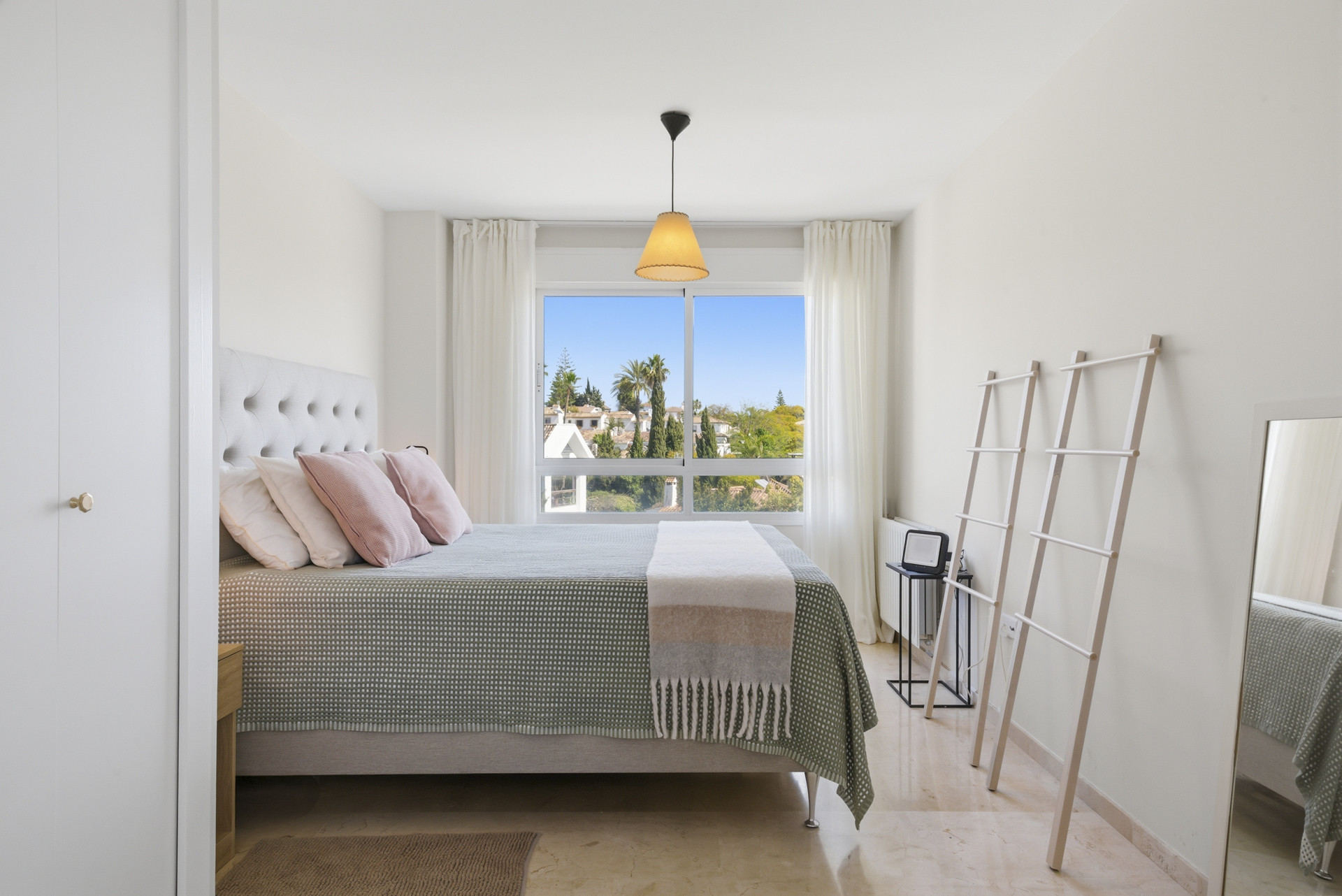 Bright bedroom featuring a double bed, side tables, and picturesque window view.
