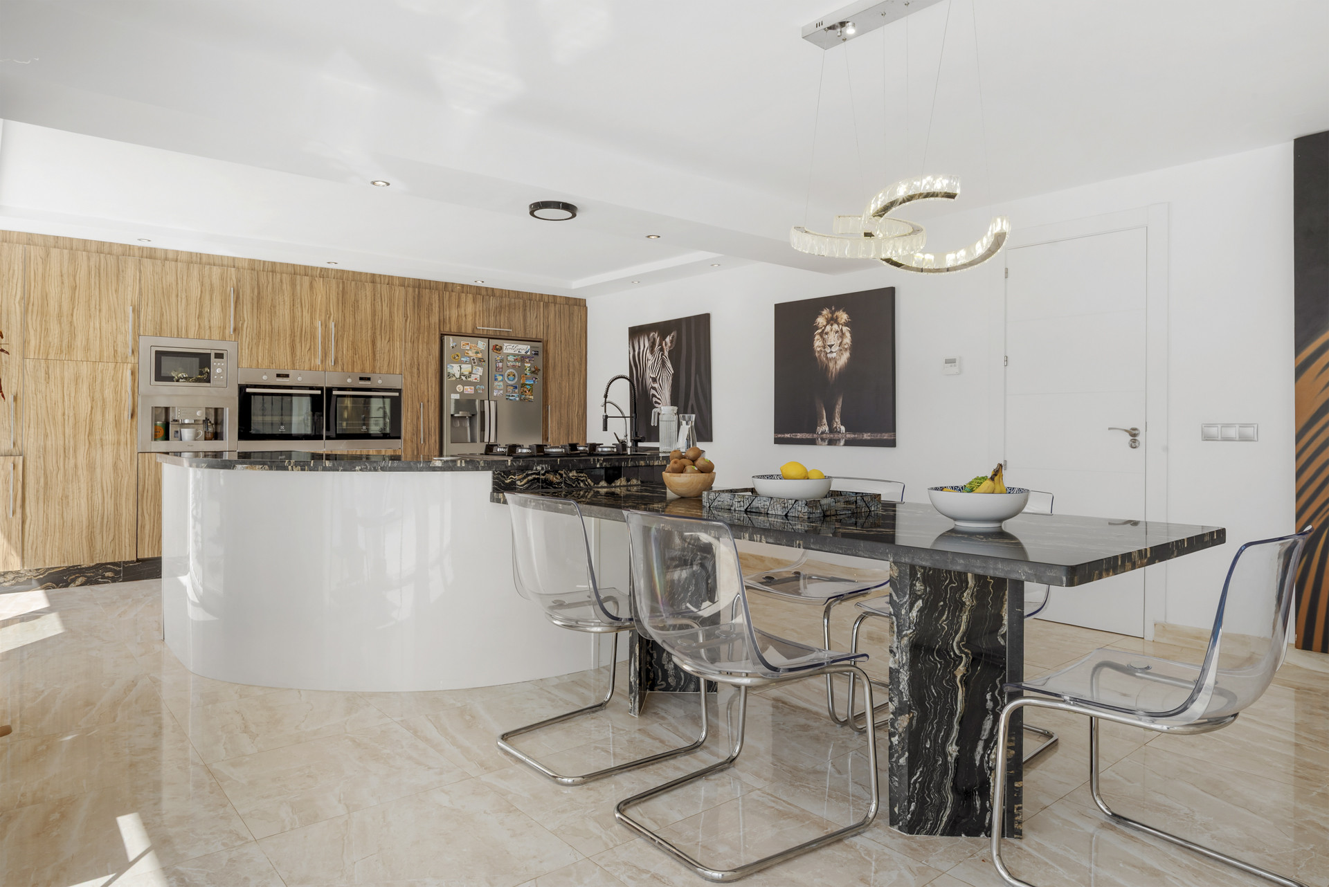Open concept kitchen with wood cabinets, black marble island and dining table, and striking art pieces.