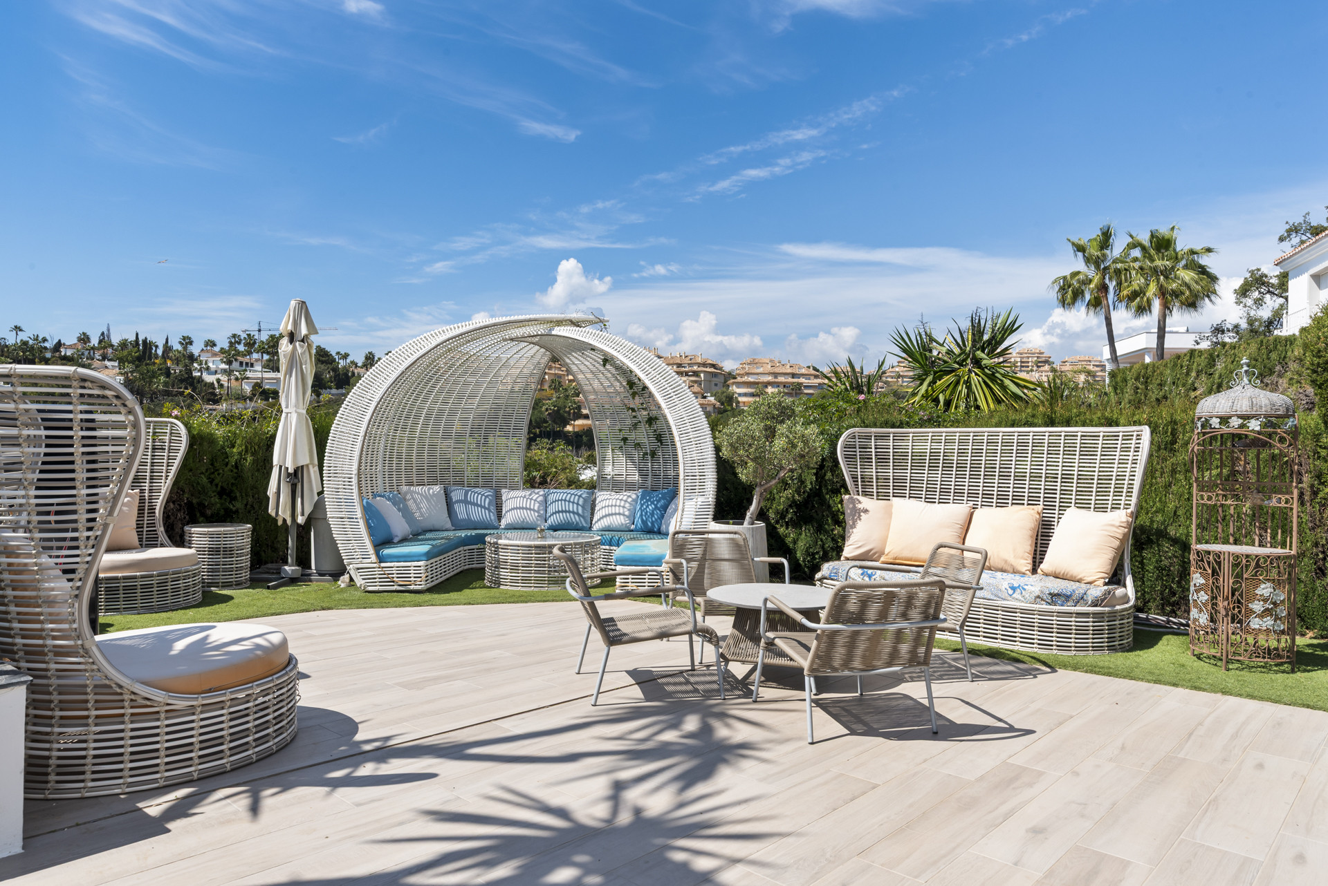 Outdoor patio with various white wicker lounge furniture, a small dining table, and green lawn.