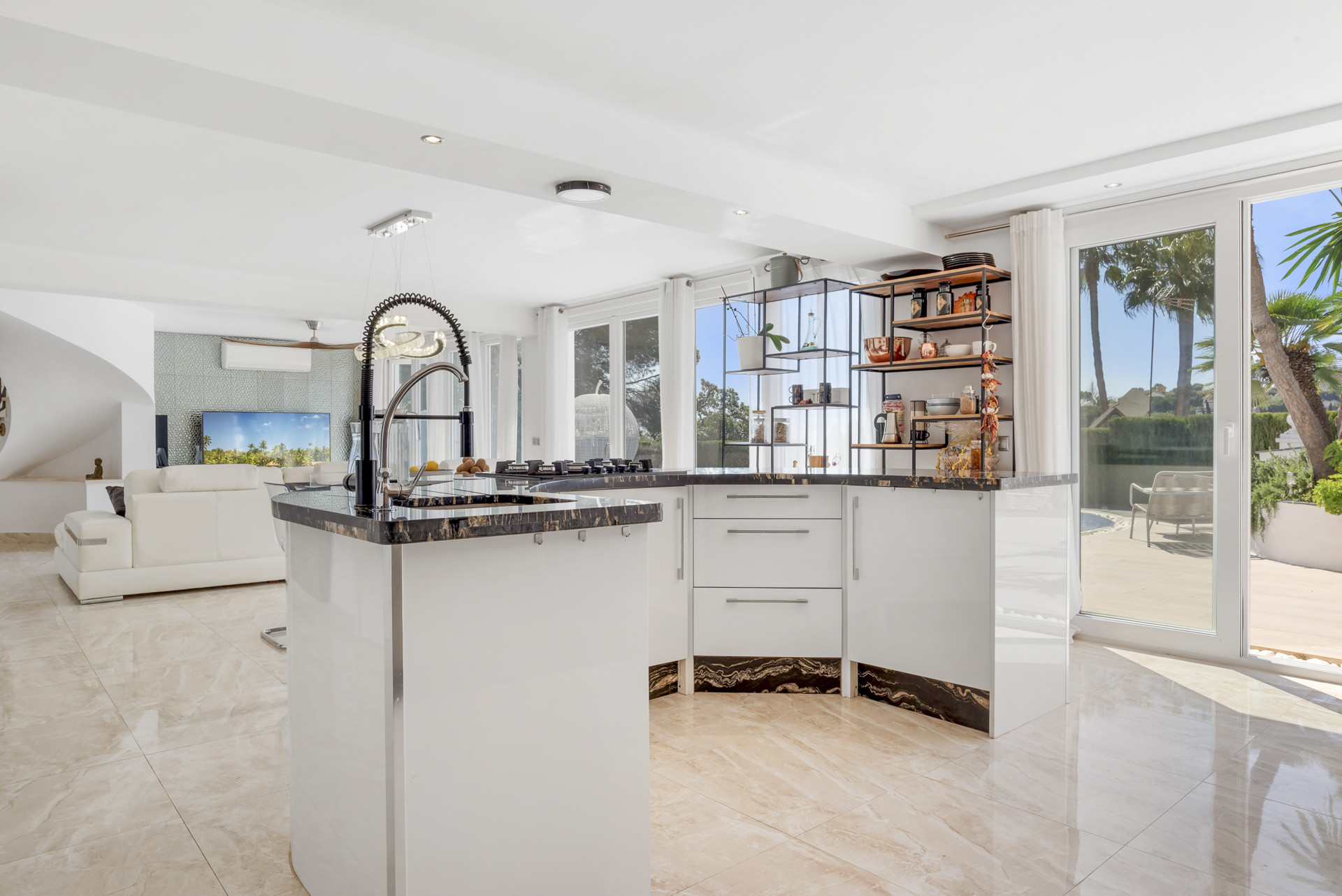 Contemporary kitchen island with integrated cooktop, white cabinets, and open shelving leading to living area.