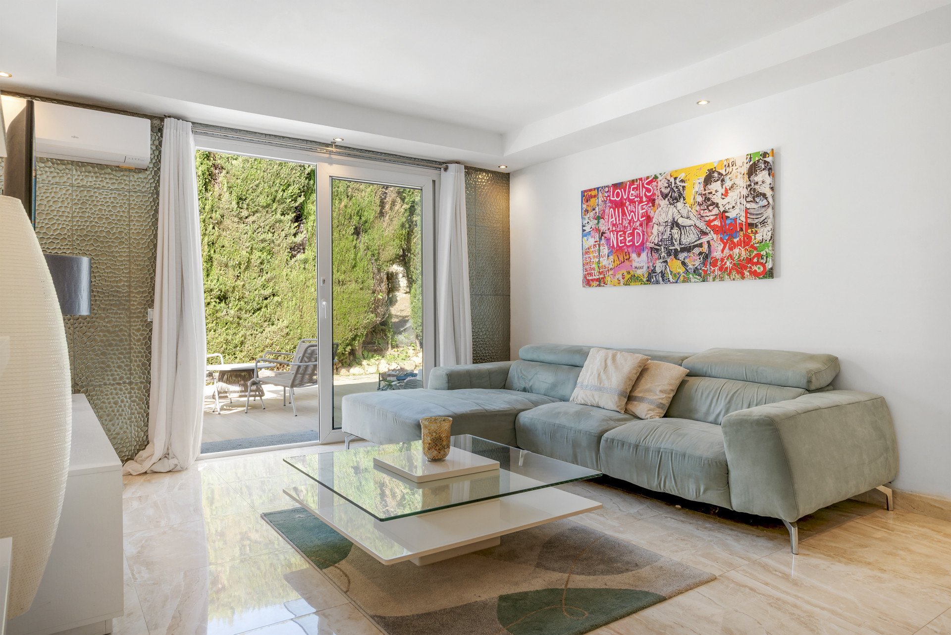 Modern living room featuring a gray sectional sofa, colorful pop art, and glass doors to a patio.