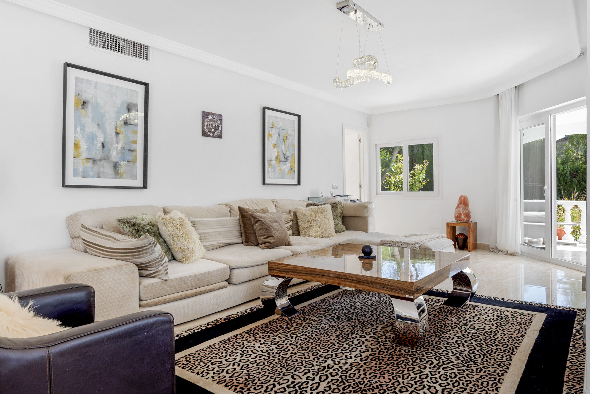 White living room with a large L-shaped sofa, coffee table, and abstract wall art.