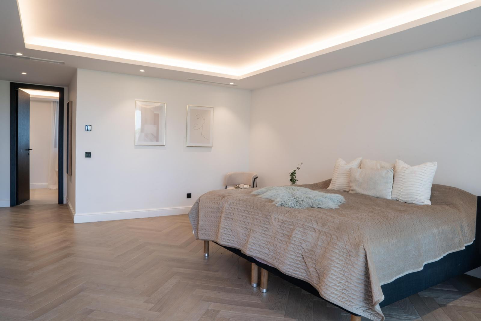 Spacious bedroom featuring a large bed with decorative pillows and modern lighting.