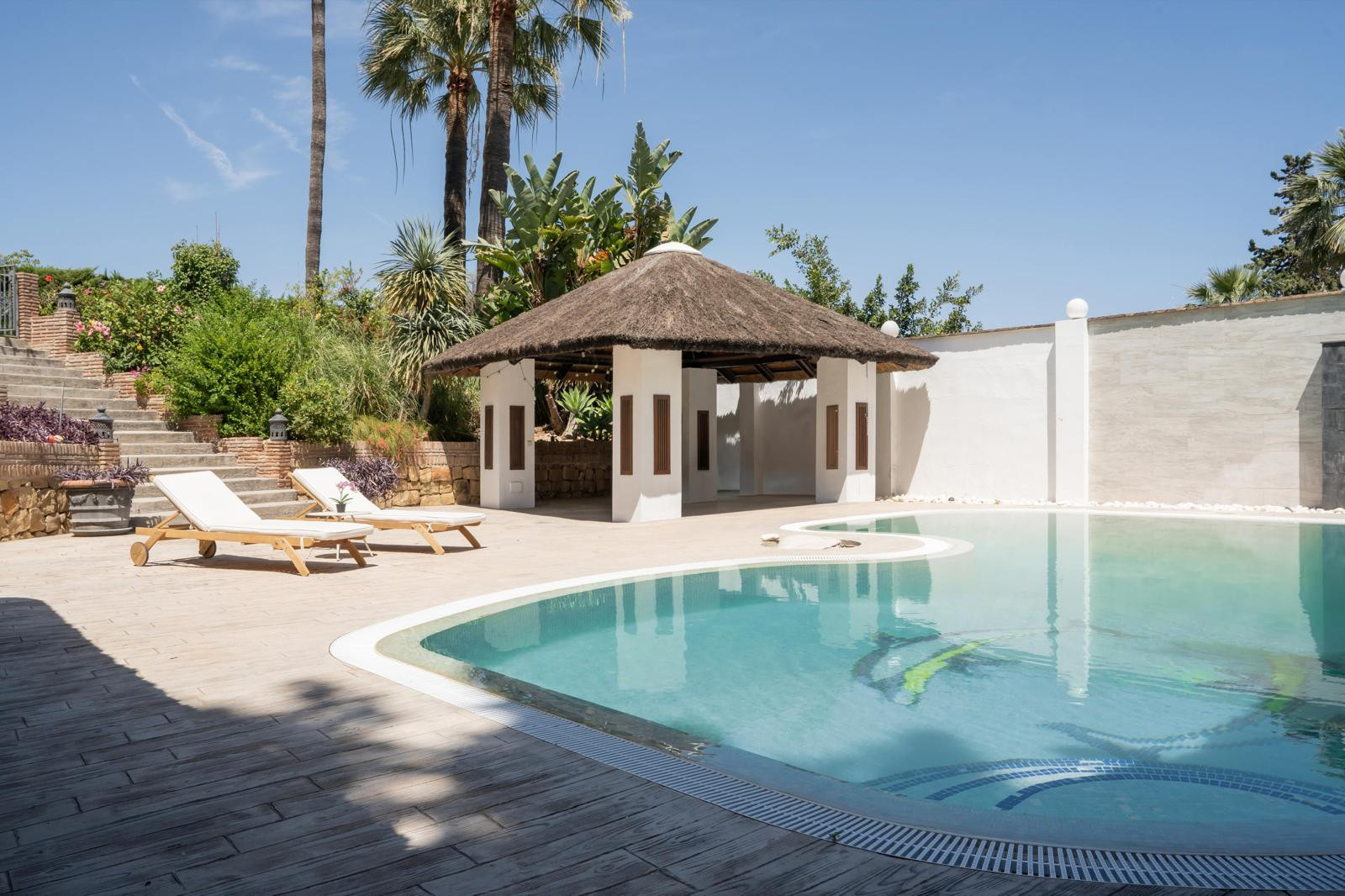 Angle showing the pool and thatched roof structure in the garden.