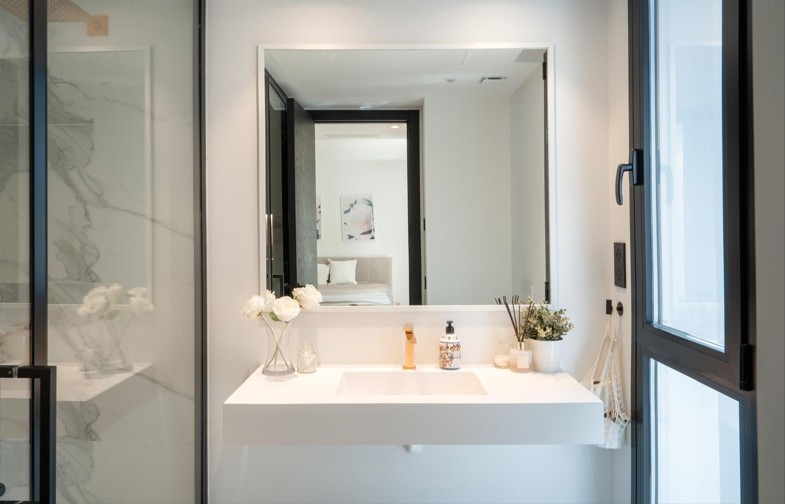 Modern bathroom with a sleek sink and large mirror, decorated with plants.