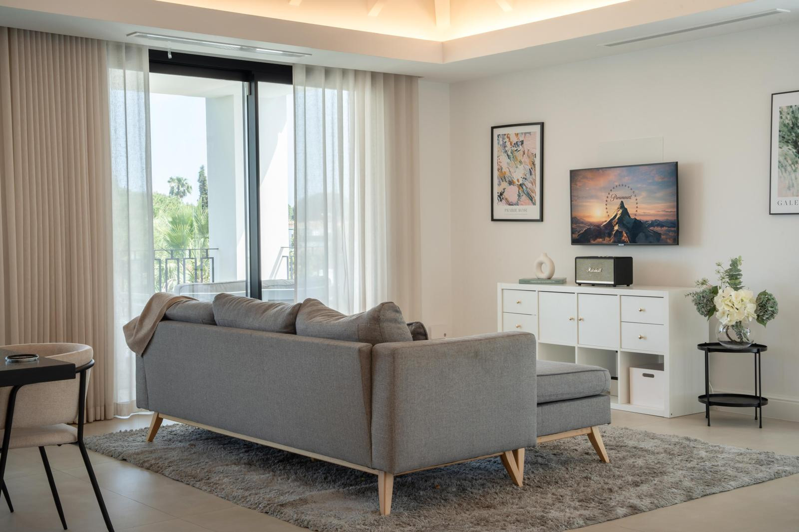 Cozy seating area with a TV, decorative items and large curtains allowing for daylight.