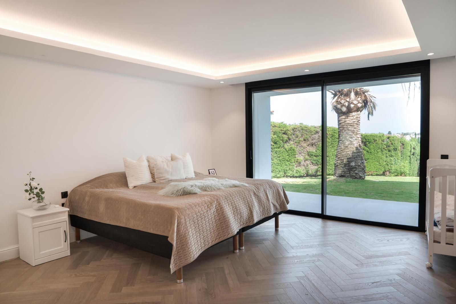Main bedroom with a large bed, decorative pillows, and a sliding door to the outdoor space.