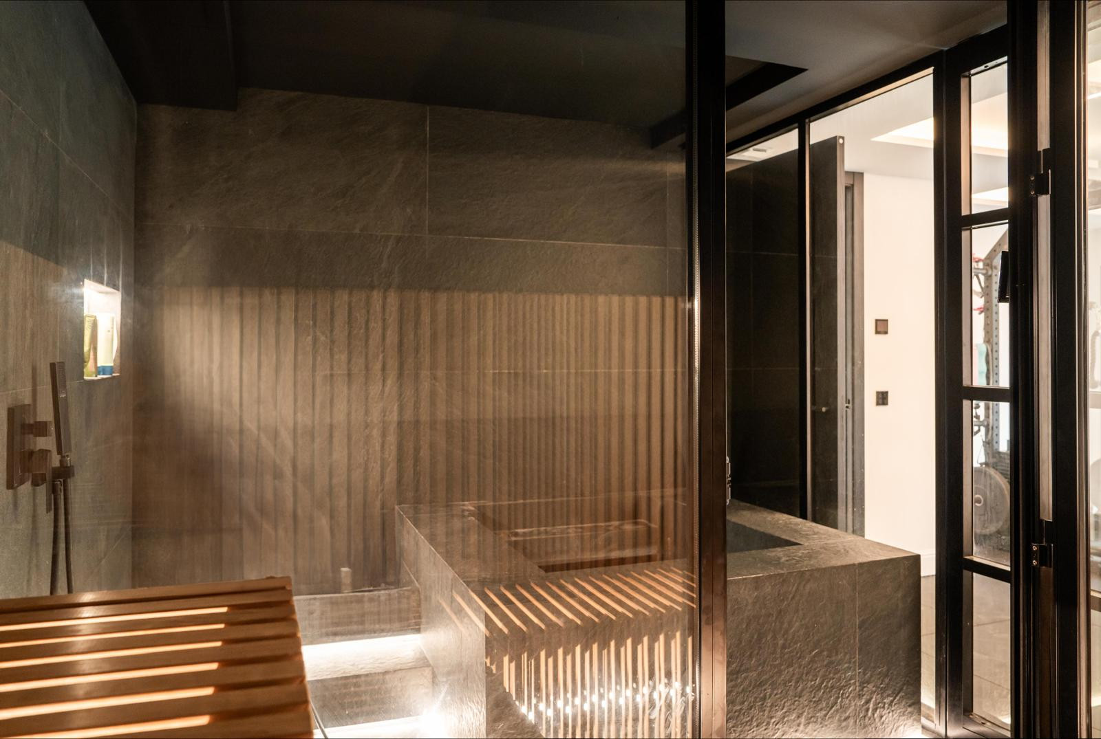Spa area with a stone bench and glass partitioning, showcasing modern design elements.