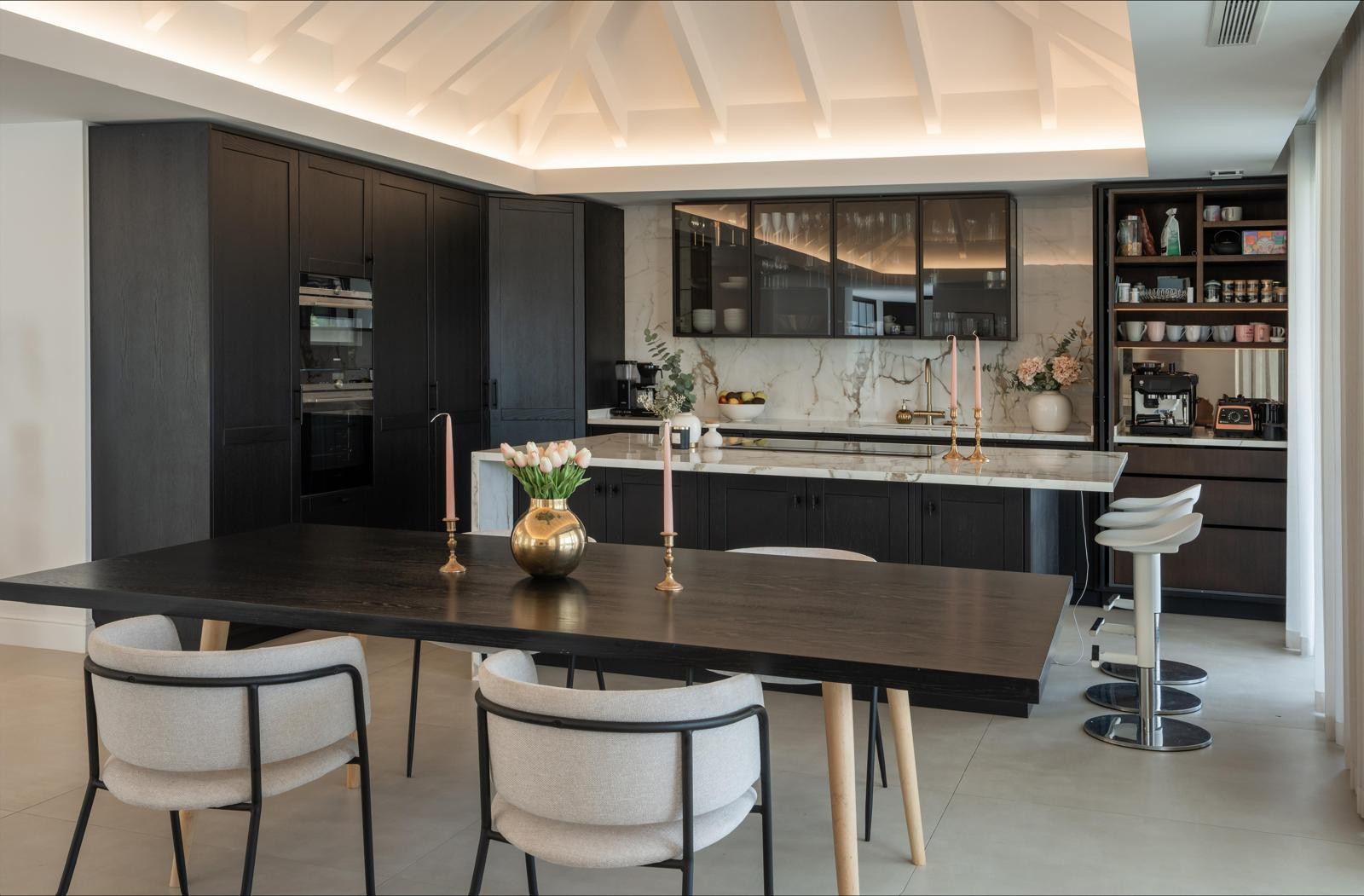 Spacious kitchen layout featuring a dining table, bar seating and elegant decor elements.