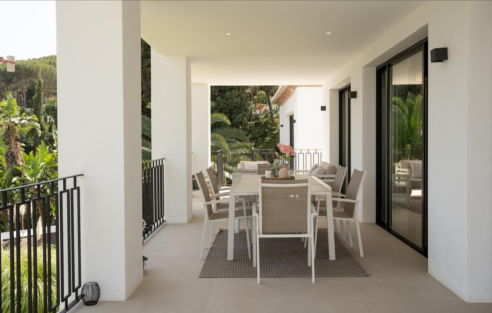 Dining area on the terrace with a table, chairs, and greenery visible in the background.