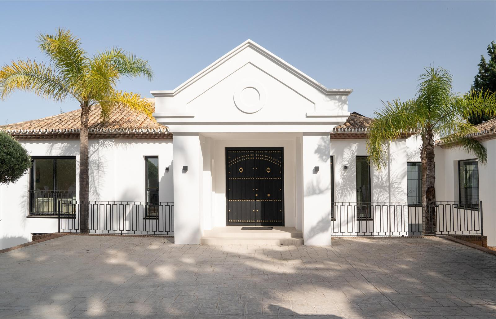 Exterior view of villa showcasing palm trees and a classic facade.