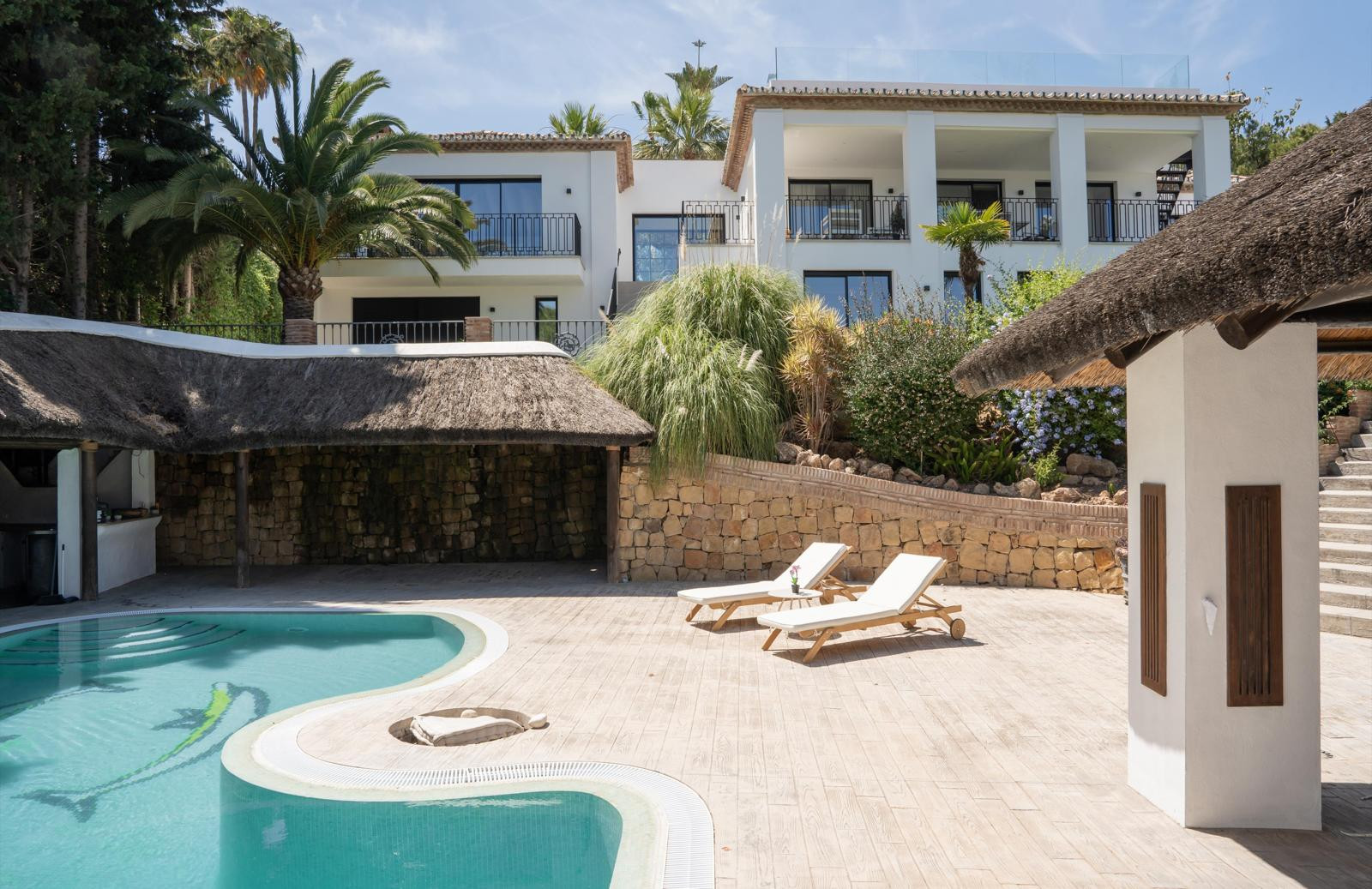 Close-up of the pool area featuring sun loungers and palm trees.