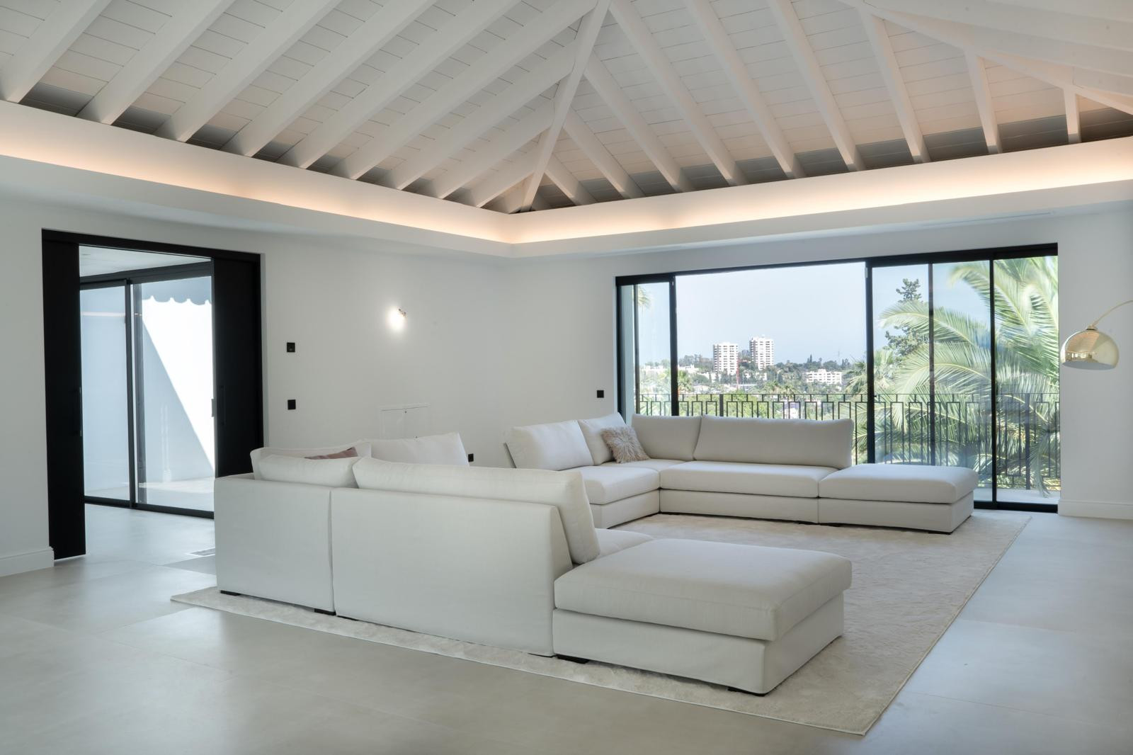 Large, bright living room with modern furniture, high ceiling, and panoramic windows.