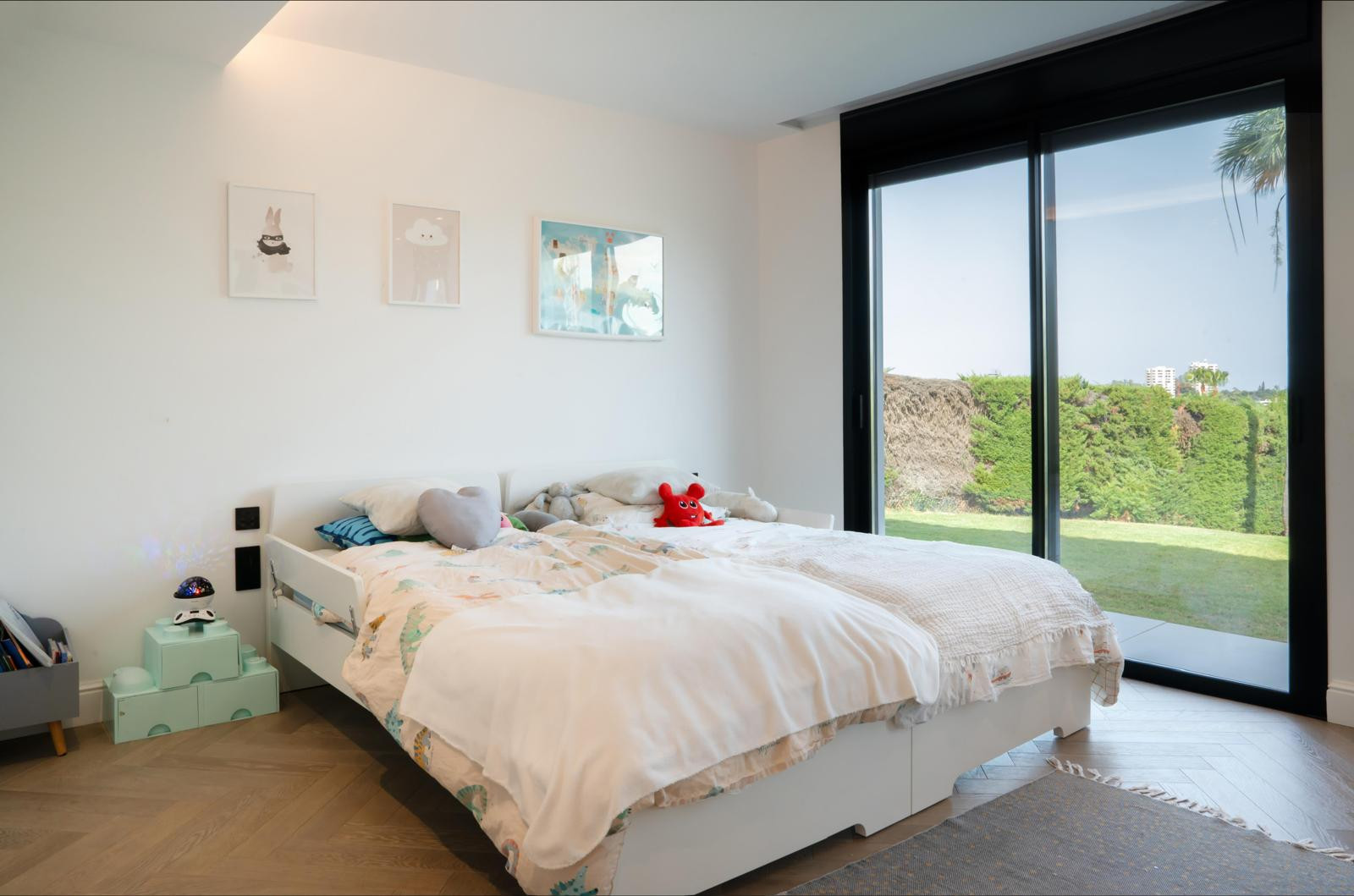 Children's bedroom featuring a bed, plush toys, and large glass doors to garden.