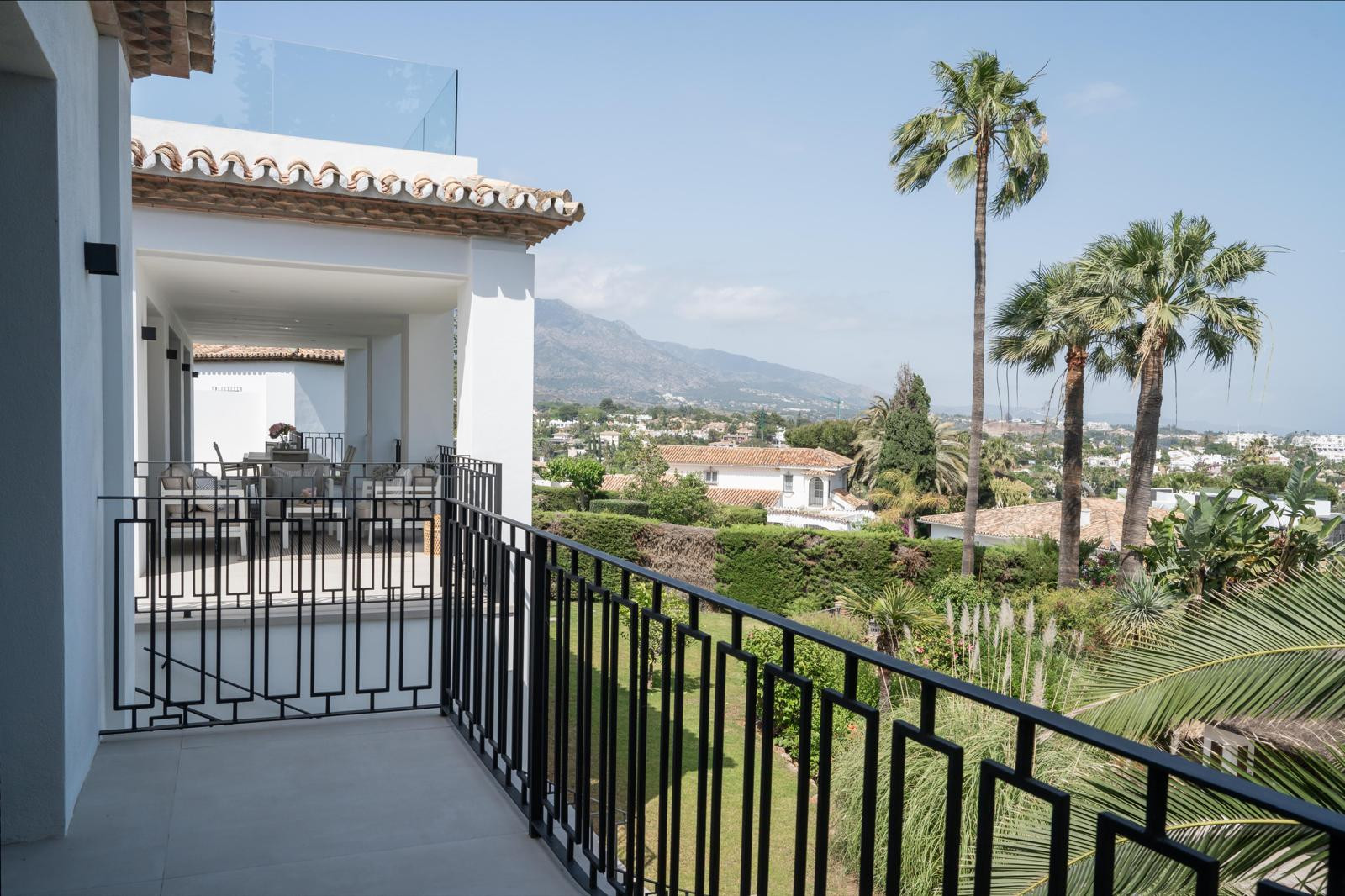 Balcony with a view of palm trees and surrounding landscape, showcasing outdoor seating.