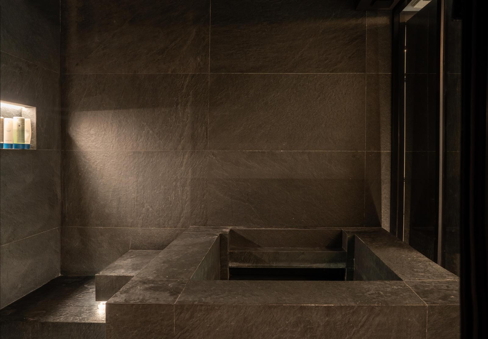Dimly lit spa area with slate tiles and a built-in seating structure.