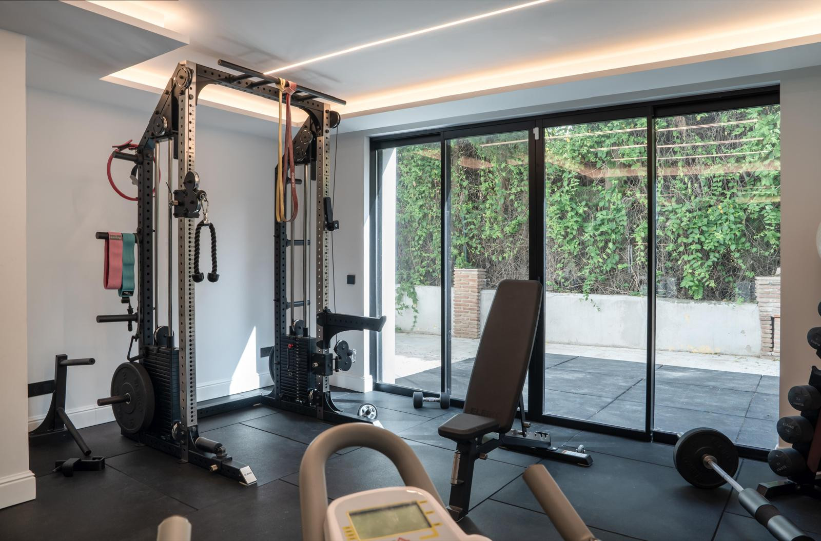 Home gym featuring a multifunctional weight machine and large windows.