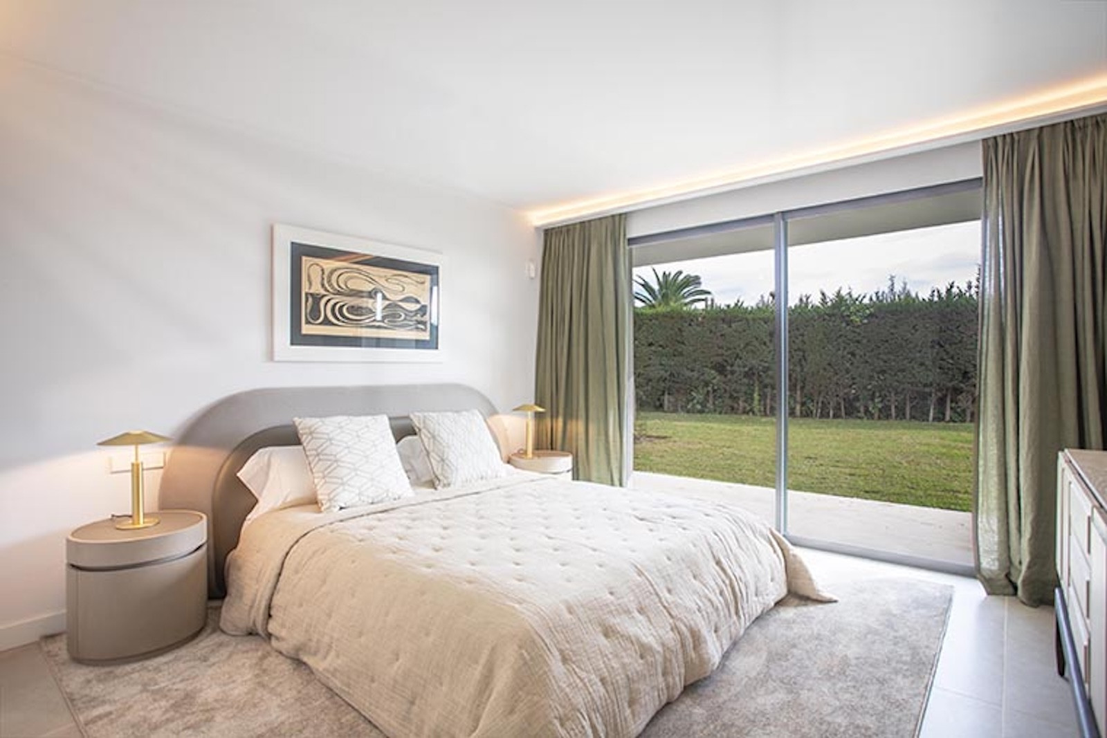 Bedroom with a bed, two nightstands with lamps, and large glass sliding doors looking out to a garden.
