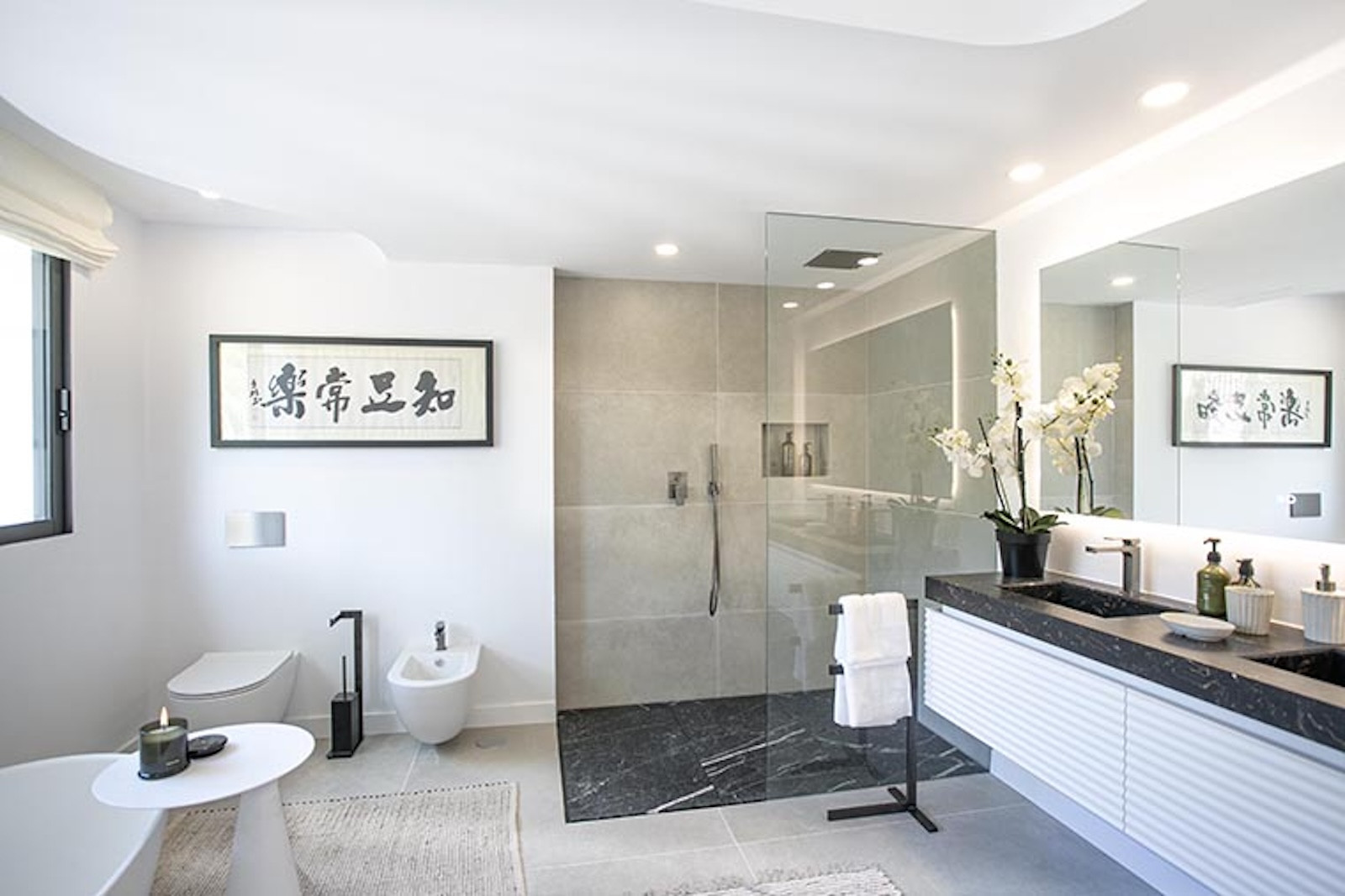 Modern bathroom with a glass shower, dual vanity, bidet, toilet, and framed artwork.