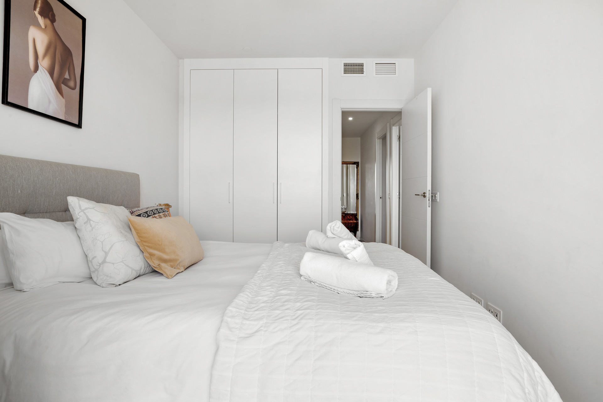 Bedroom featuring a bed with white linen, a gray headboard, and a built-in white wardrobe.