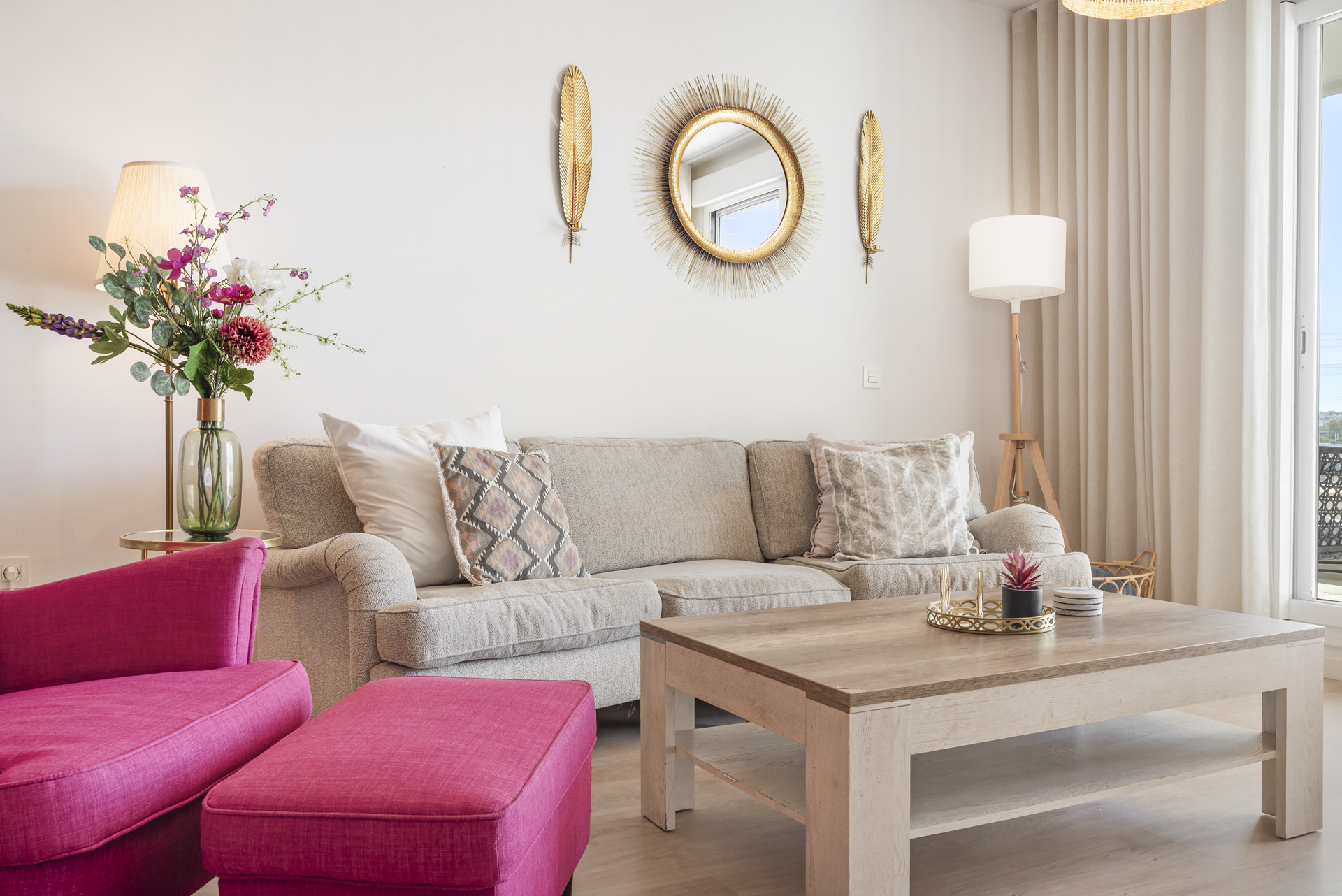 Living room with a light gray sofa, wooden coffee table, gold mirror, and floor lamp.