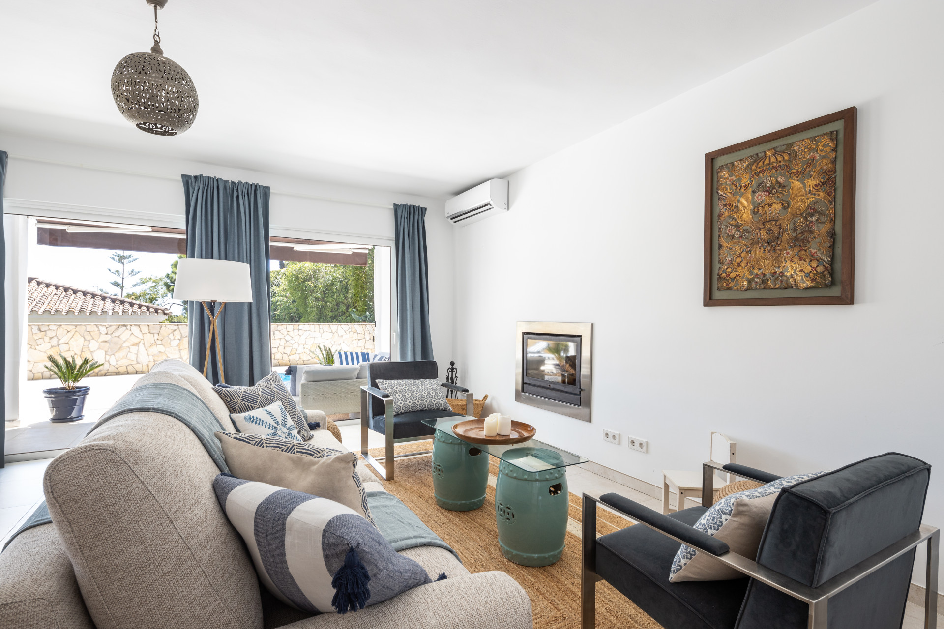 Living room showing a beige sofa, modern fireplace, and glass sliding doors leading to an outdoor area.