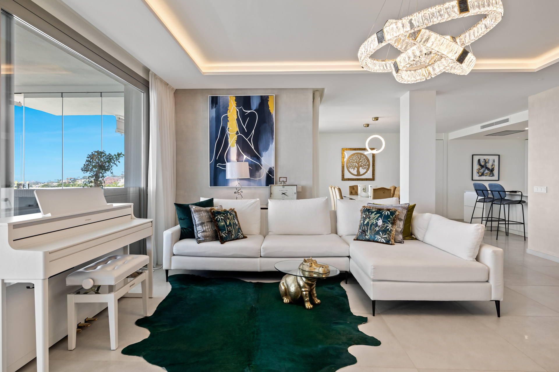 Living room showcasing a white sectional sofa, white baby grand piano, and balcony access.