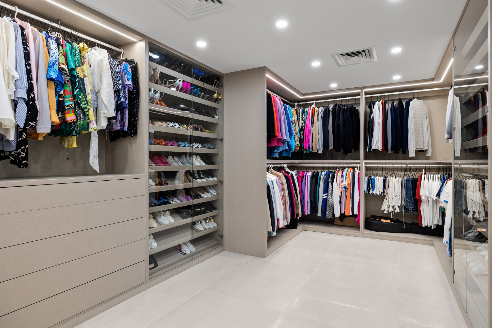 Large walk-in closet with extensive hanging space and shoe storage in light-colored wood.