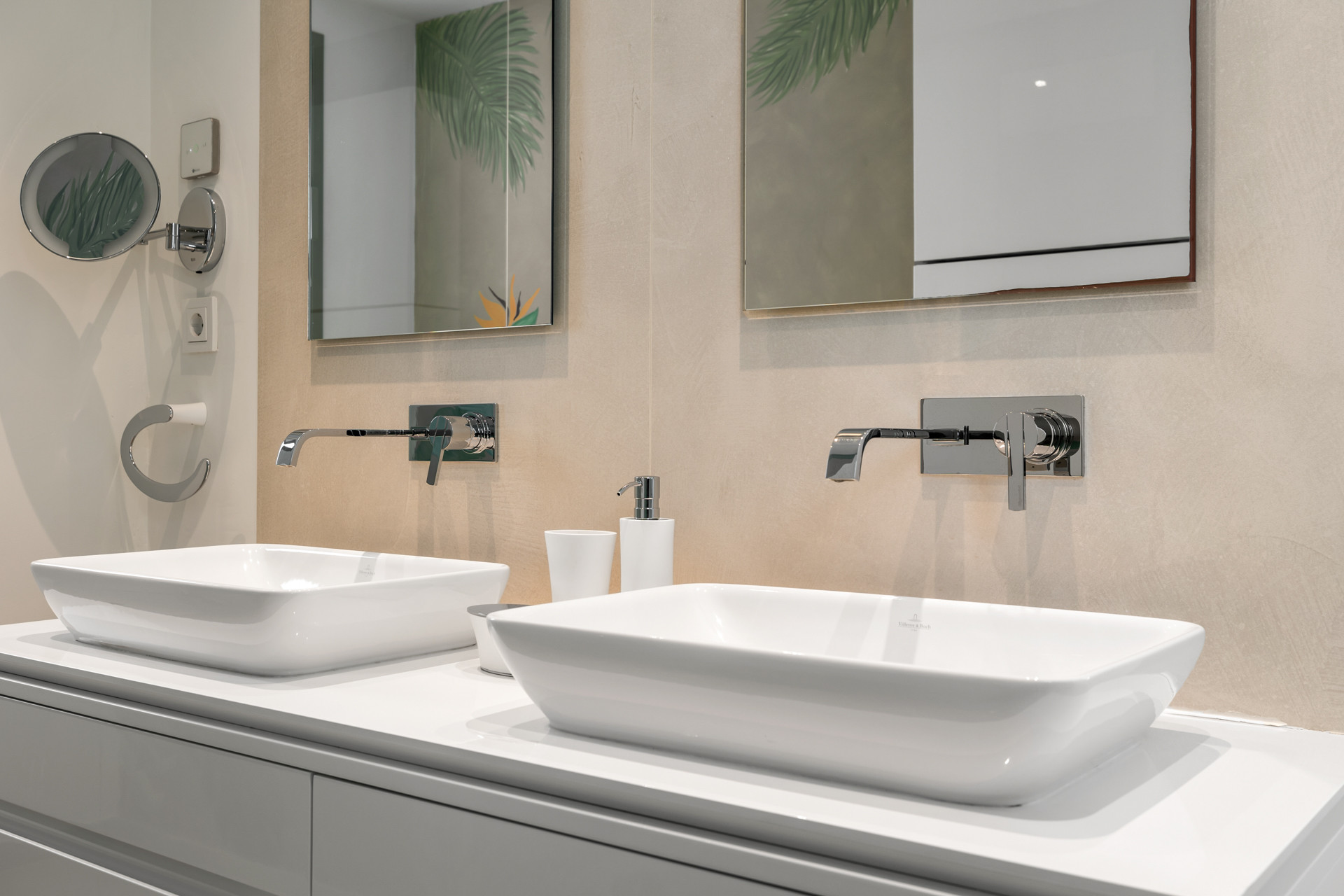 Close up of two white rectangular vessel sinks with chrome wall-mounted faucets and mirrors.