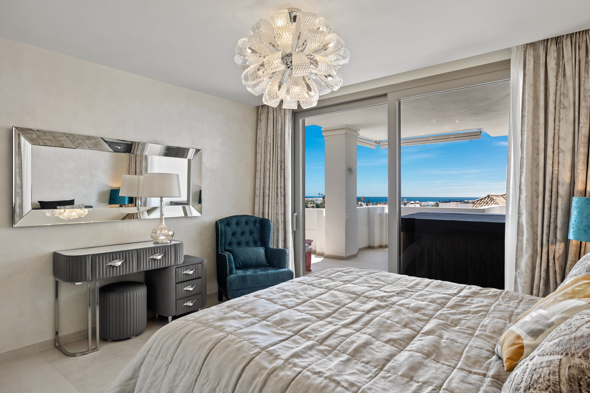 Bedroom with bed, vanity, armchair, and sliding glass doors to a balcony with sea views.