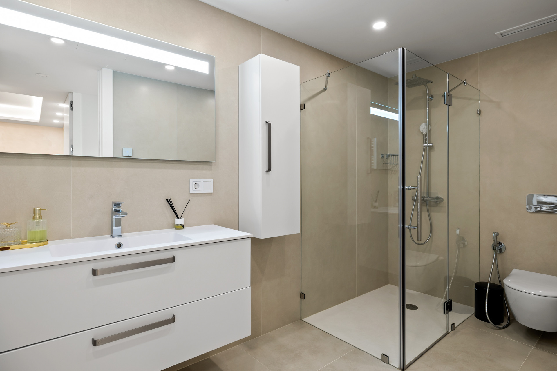 Bathroom featuring a modern white vanity, large mirror, glass shower, and a toilet.