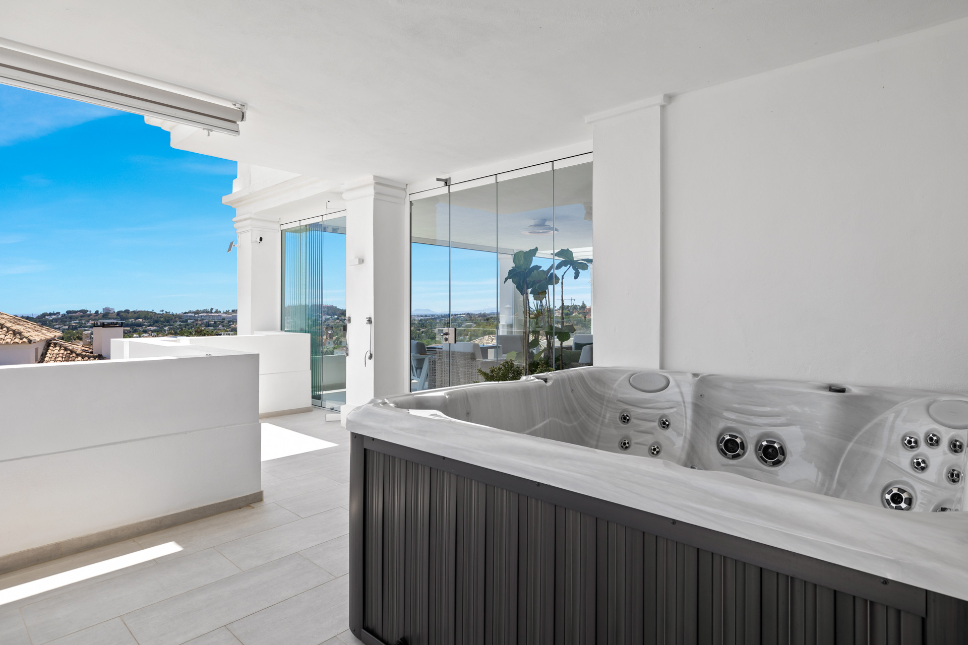 Corner view of an outdoor hot tub on a patio with distant city and mountain views.