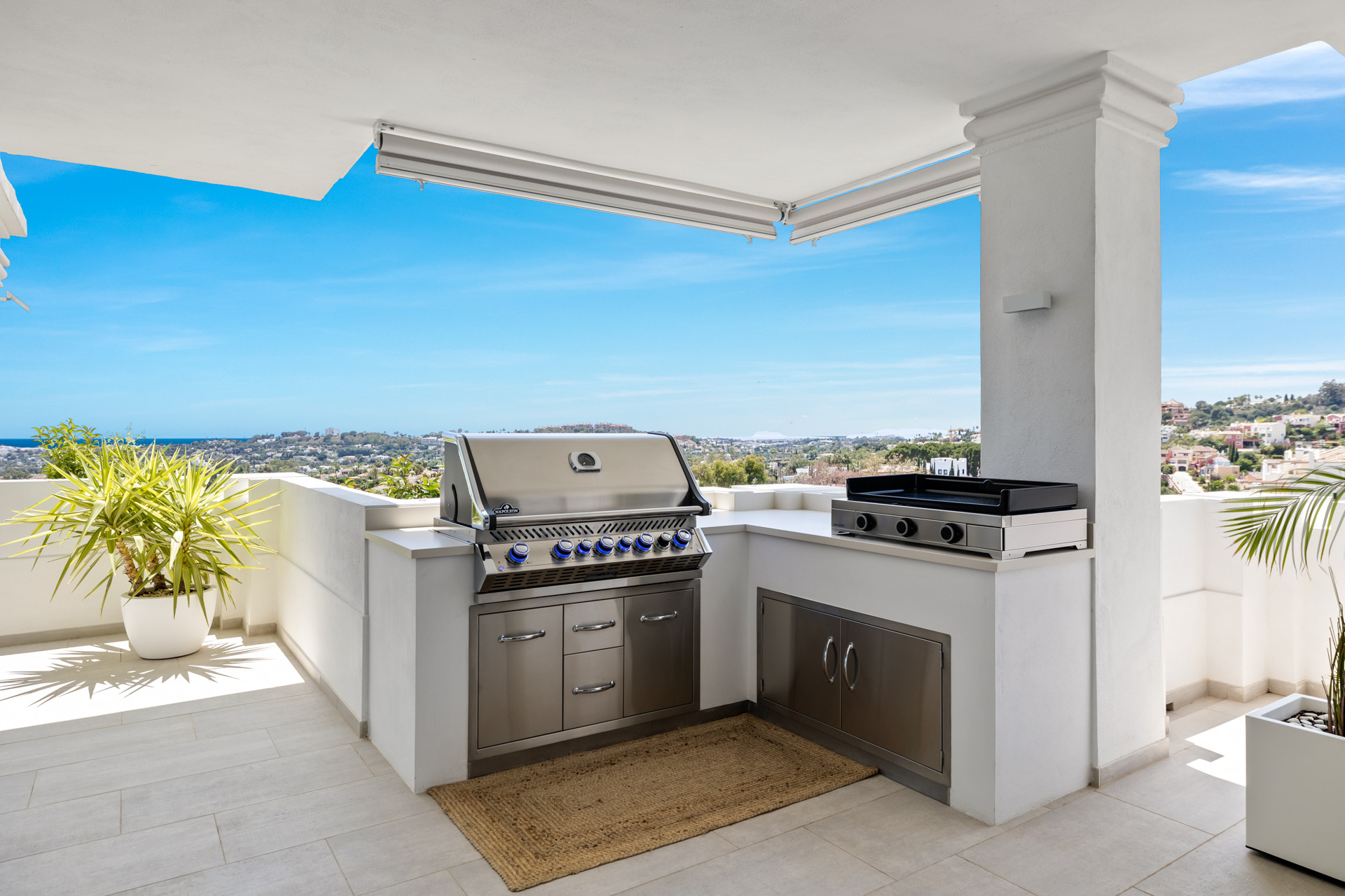 Rooftop terrace with a stainless steel grill, a flat-top griddle, and a panoramic view of the coast.