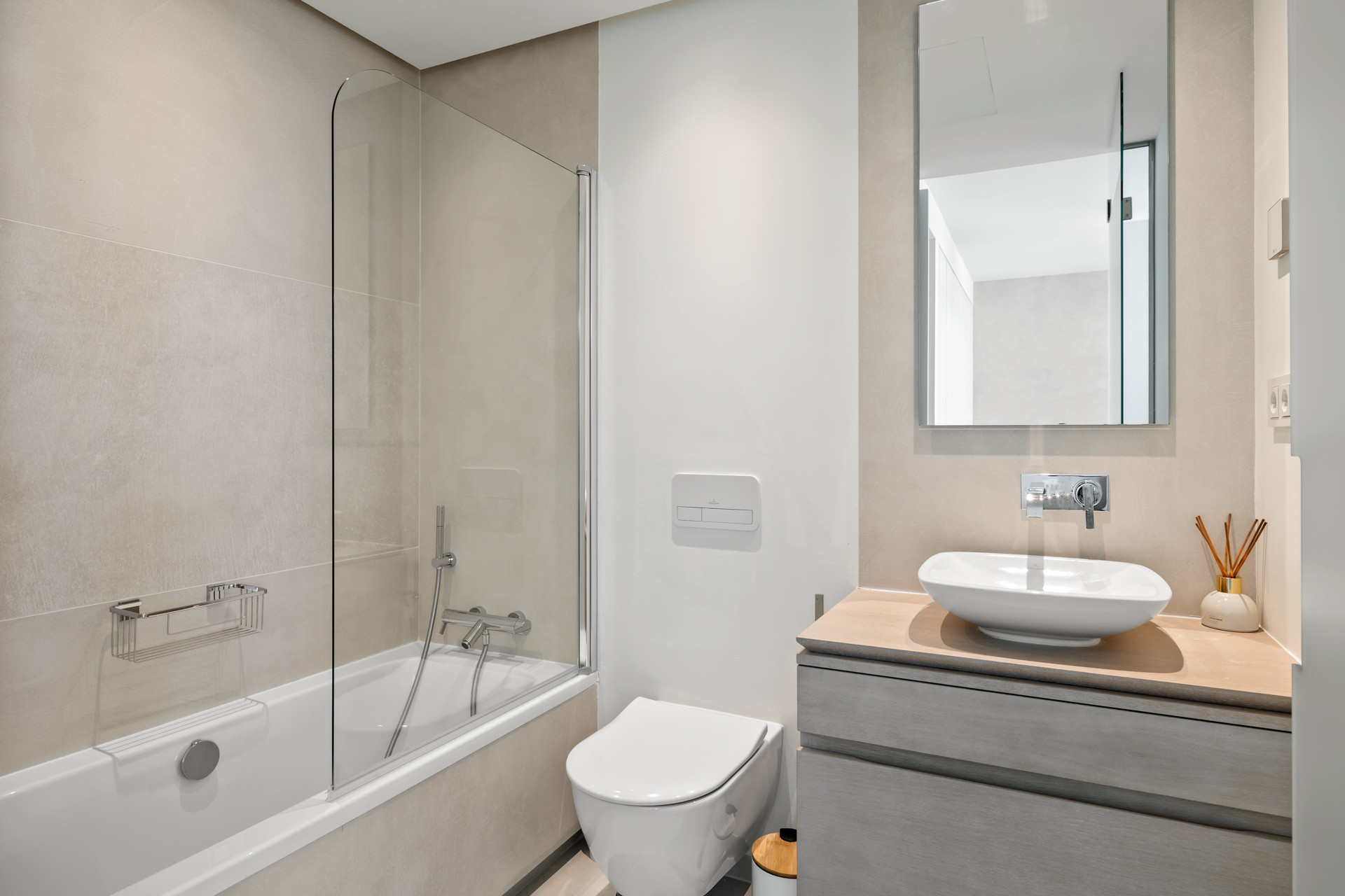 Modern bathroom with a bathtub and glass shower screen, toilet, and vanity with a vessel sink and mirror.