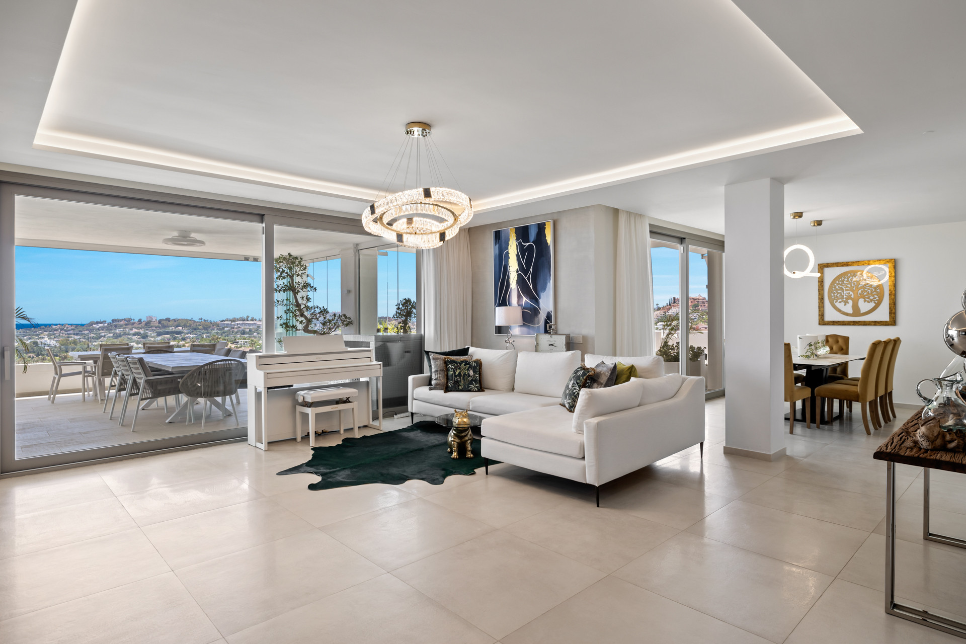 Spacious living room featuring a white sectional sofa, baby grand piano, and balcony with city views.