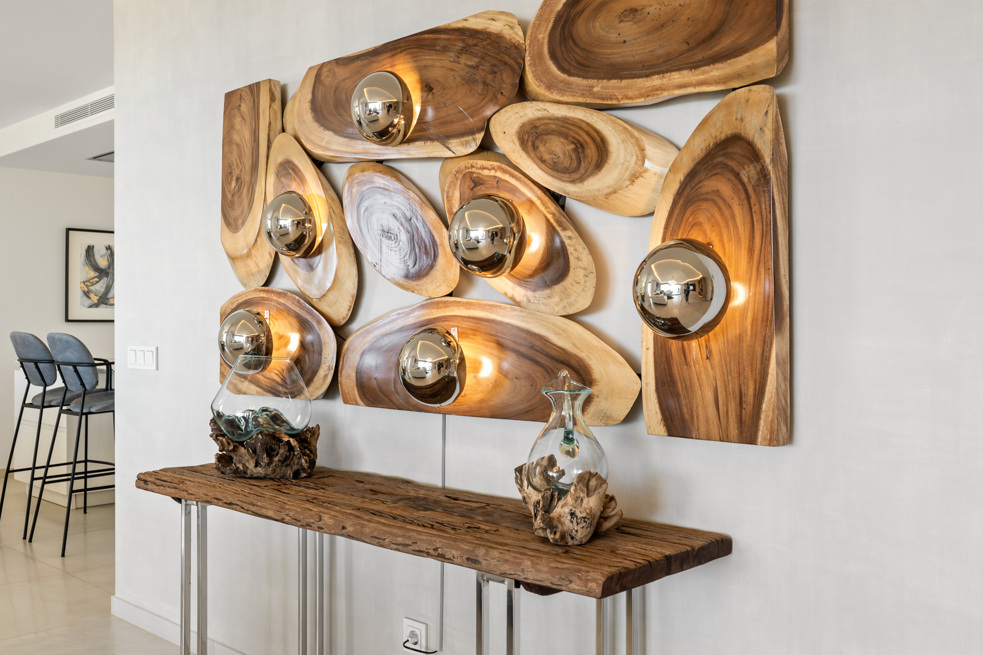 Entryway area with a console table made of wood slab, decorated with a large wooden art piece on the wall.