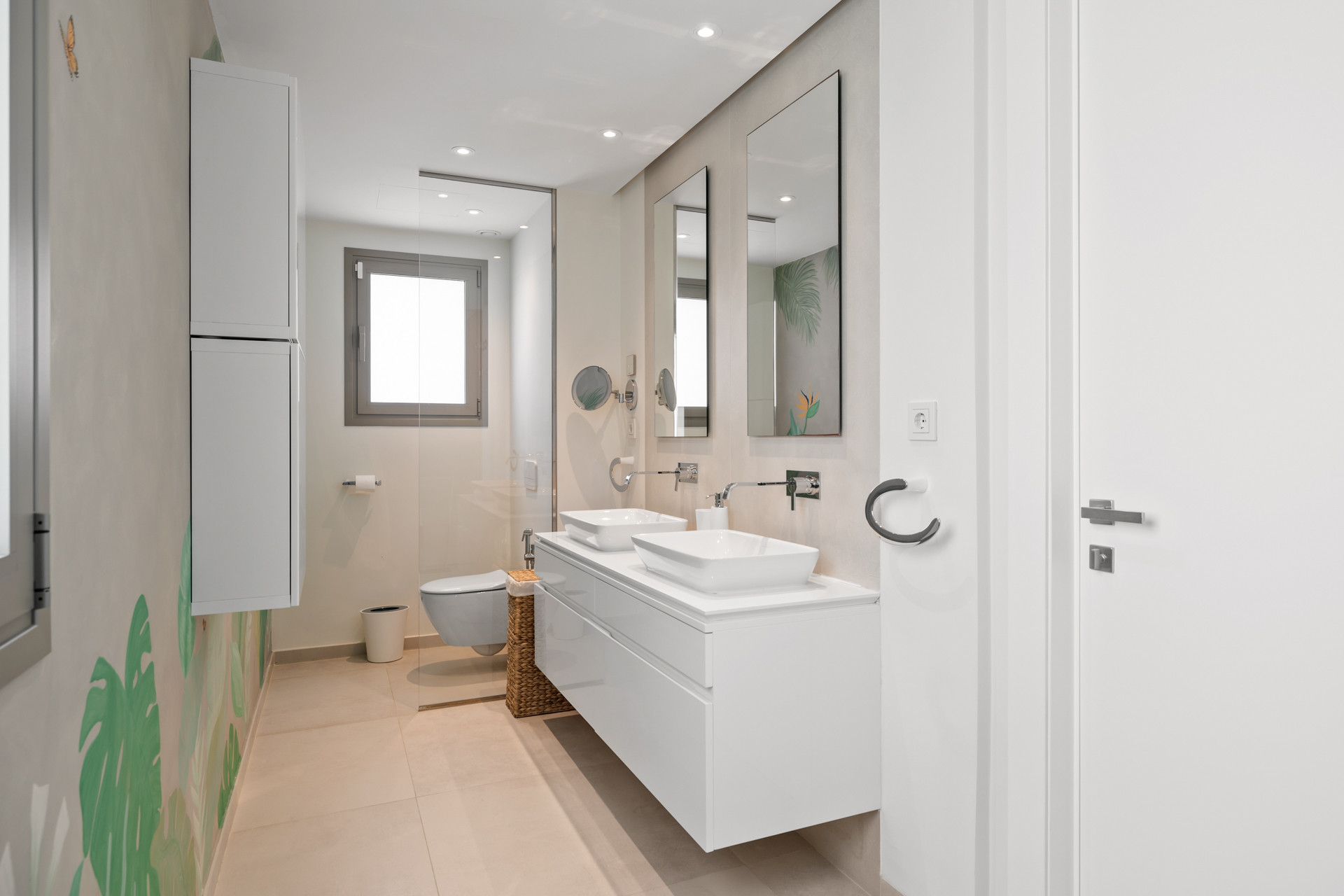 Modern bathroom with a dual vanity, white cabinetry, a toilet, and a glass-enclosed shower.