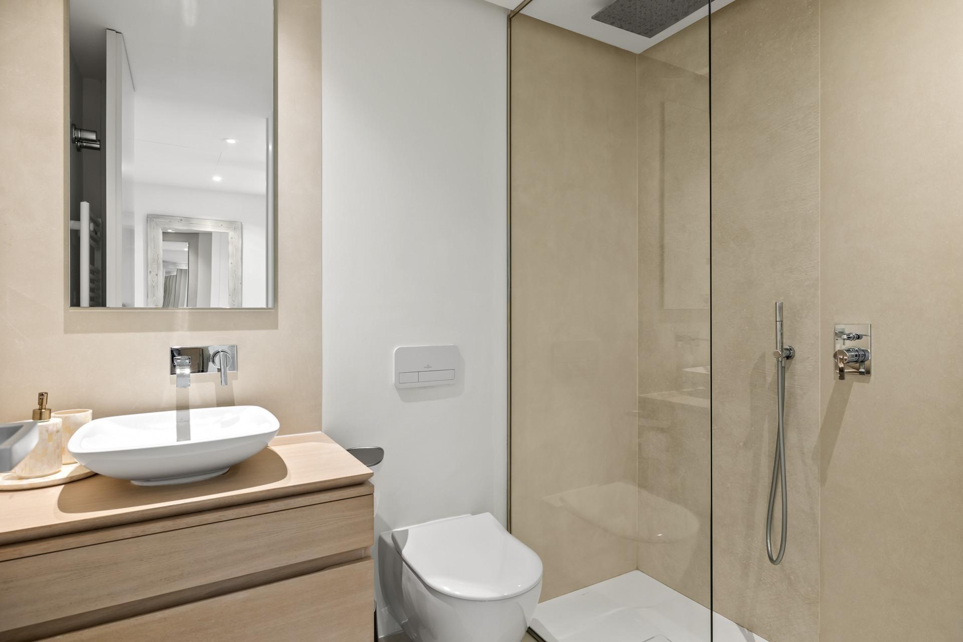Bathroom with a wooden vanity, vessel sink, wall mounted toilet, and a glass enclosed shower.