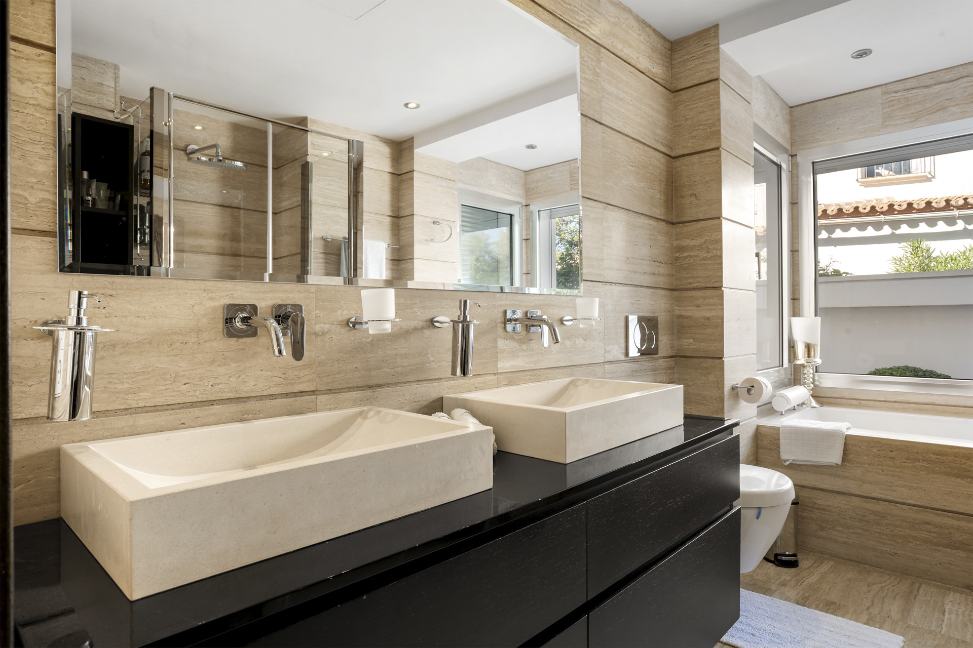 Bathroom featuring a double floating vanity, stone vessel sinks, a large mirror, and a toilet.
