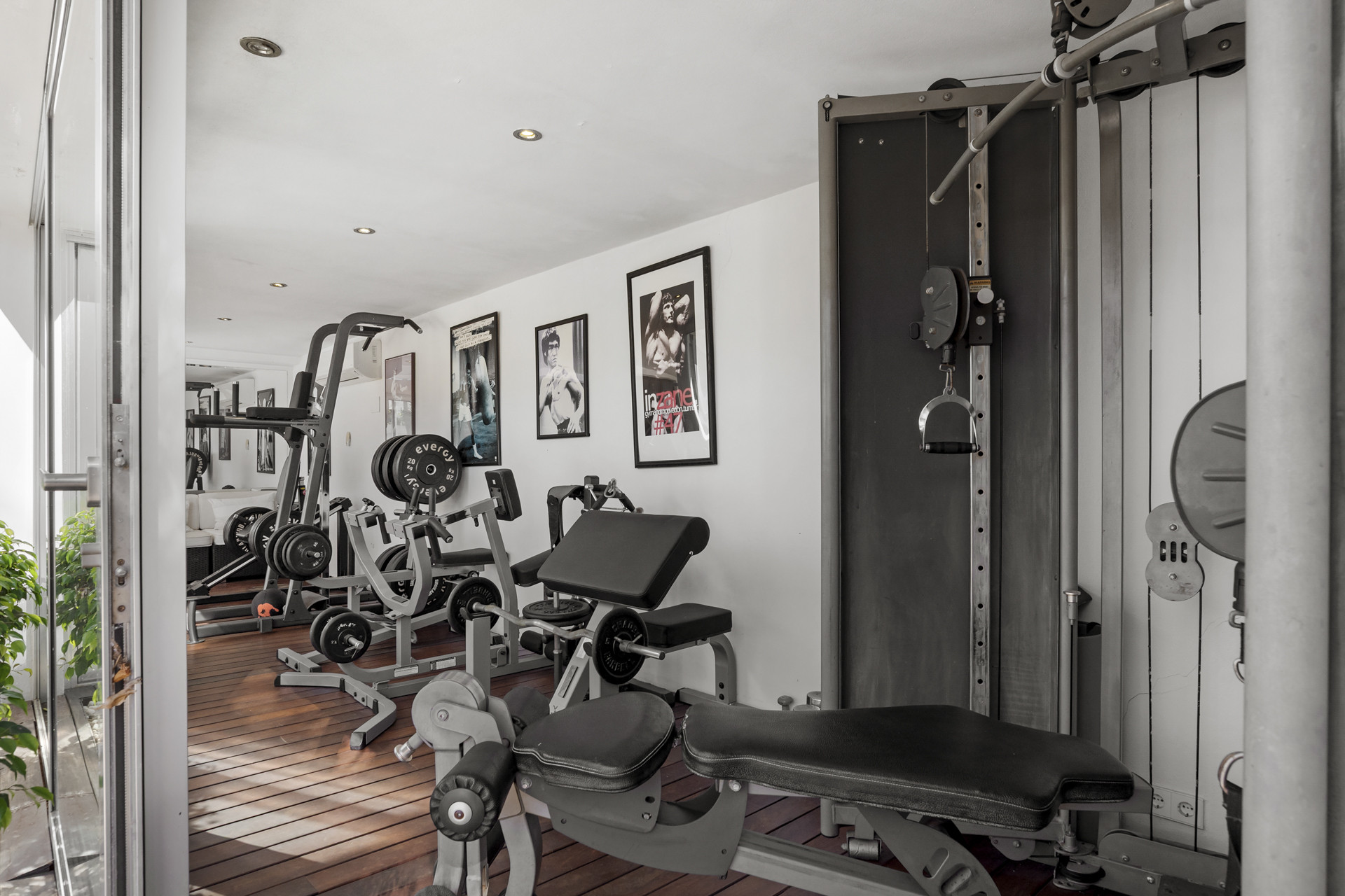 Home gym with various weight machines, benches, and framed art on the wall.