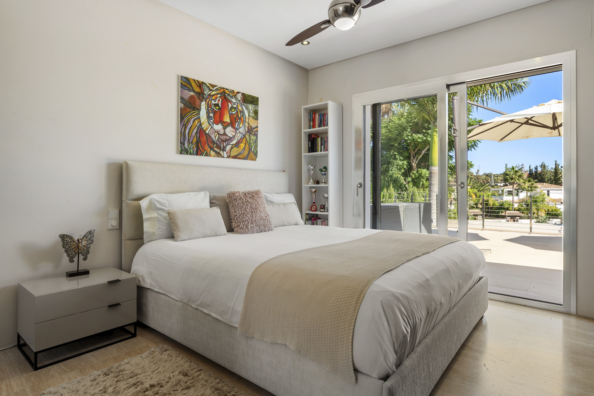 Bedroom with a bed, nightstand, colorful tiger art, and sliding door to a balcony.