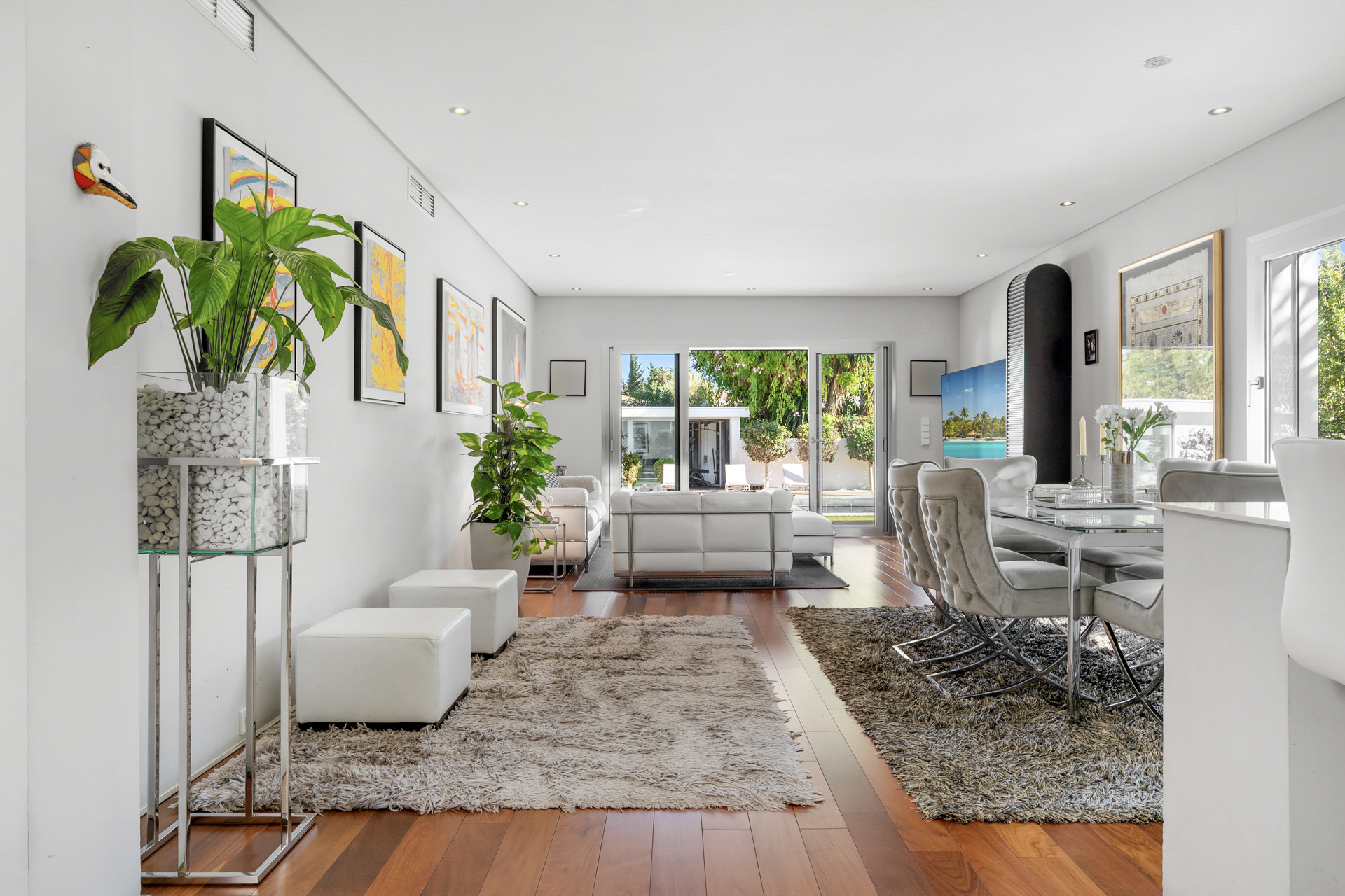 Spacious living room with a dining area, white furniture, hardwood floors, and sliding glass doors to a patio.