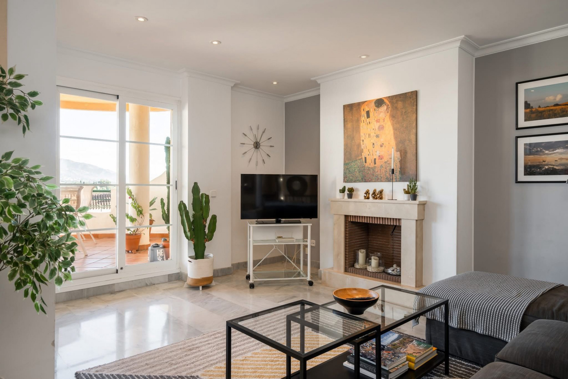 Living room with a fireplace, TV, large artwork, and glass doors opening to an outdoor patio.